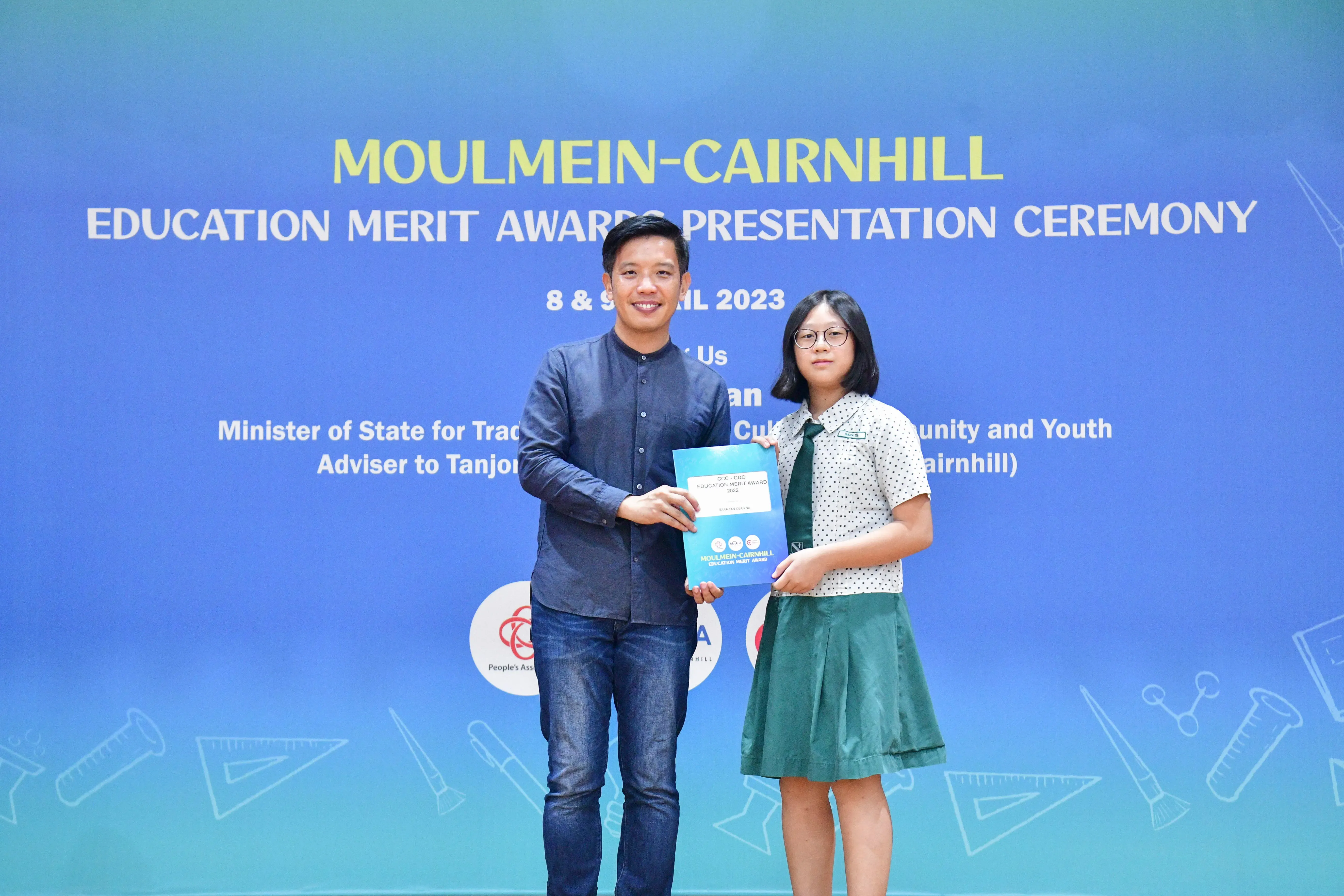 A man and a young girl hold a certificate together at the Moulmein-Cairnhill Education Merit Award Ceremony 2023.