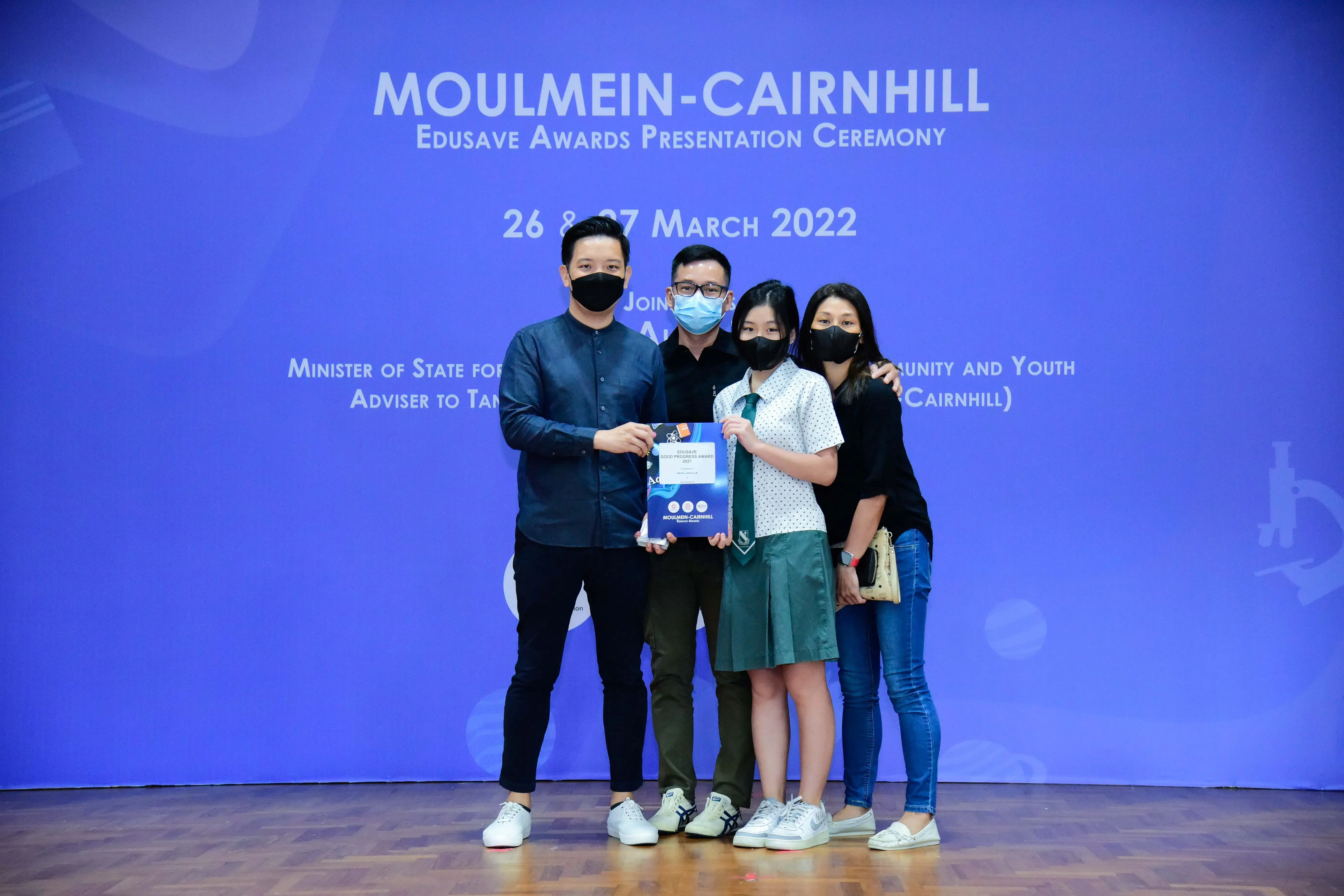 Four masked people pose with an award at the Moulmein-Cairnhill Edusave Awards Ceremony, March 2022.