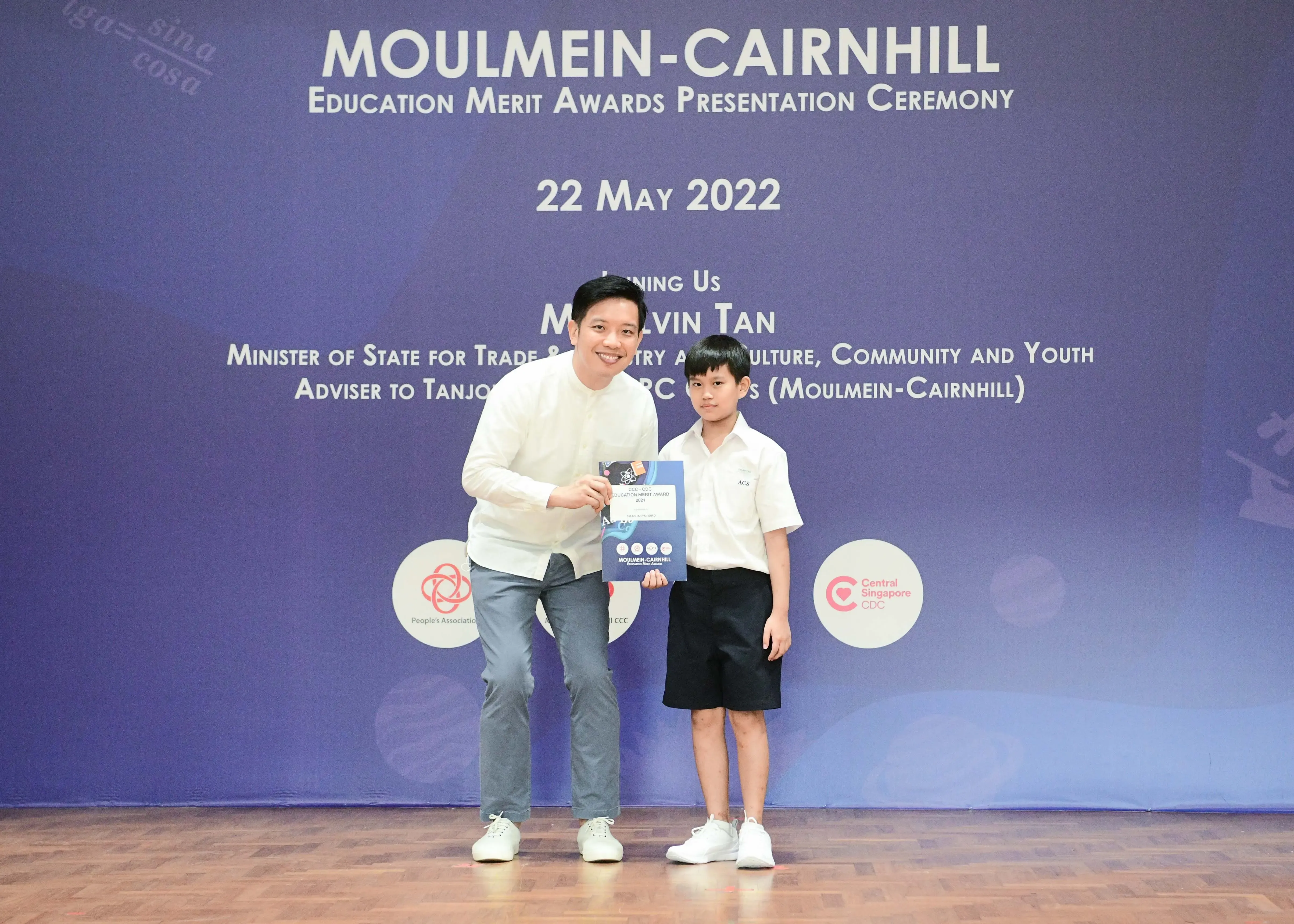 A man and a young boy hold an award certificate at the Moulmein-Cairnhill Education Merit Awards Ceremony, 22 May 2022.