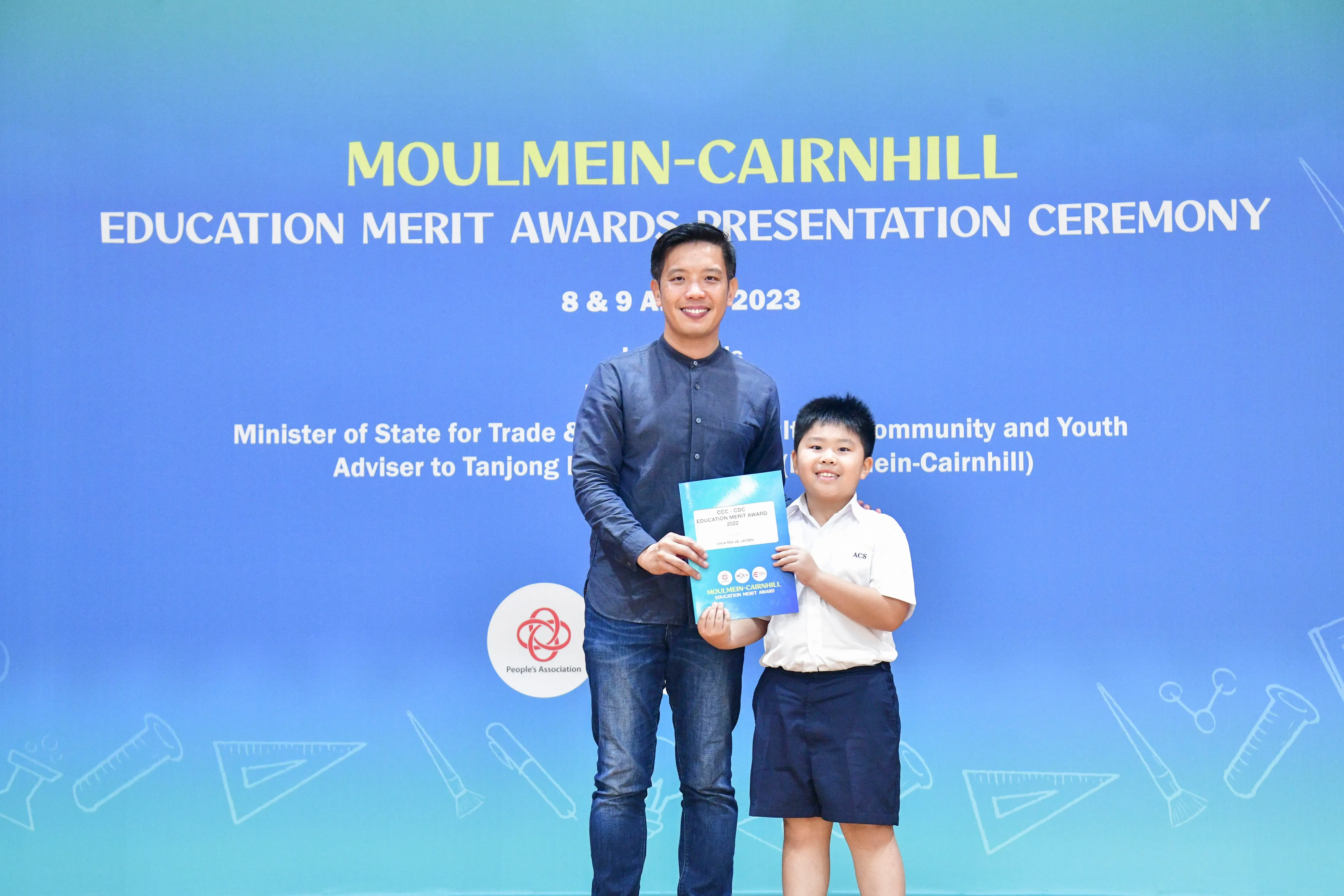 A man and a young boy in school uniform hold an award certificate at the Moulmein-Cairnhill Education Merit Awards 2023.