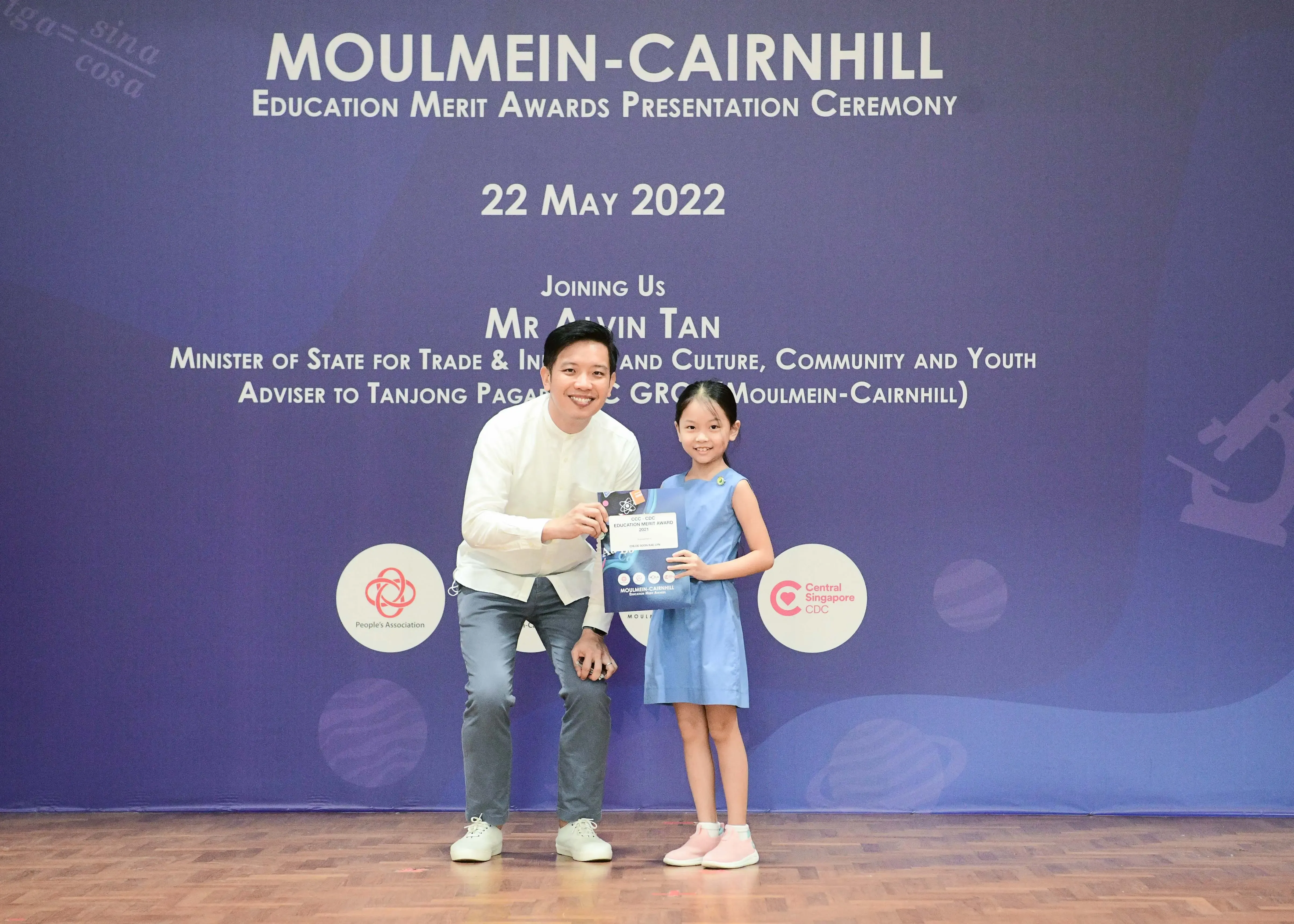 A man and a young girl hold a certificate at the Moulmein-Cairnhill Education Merit Awards Ceremony on 22 May 2022.