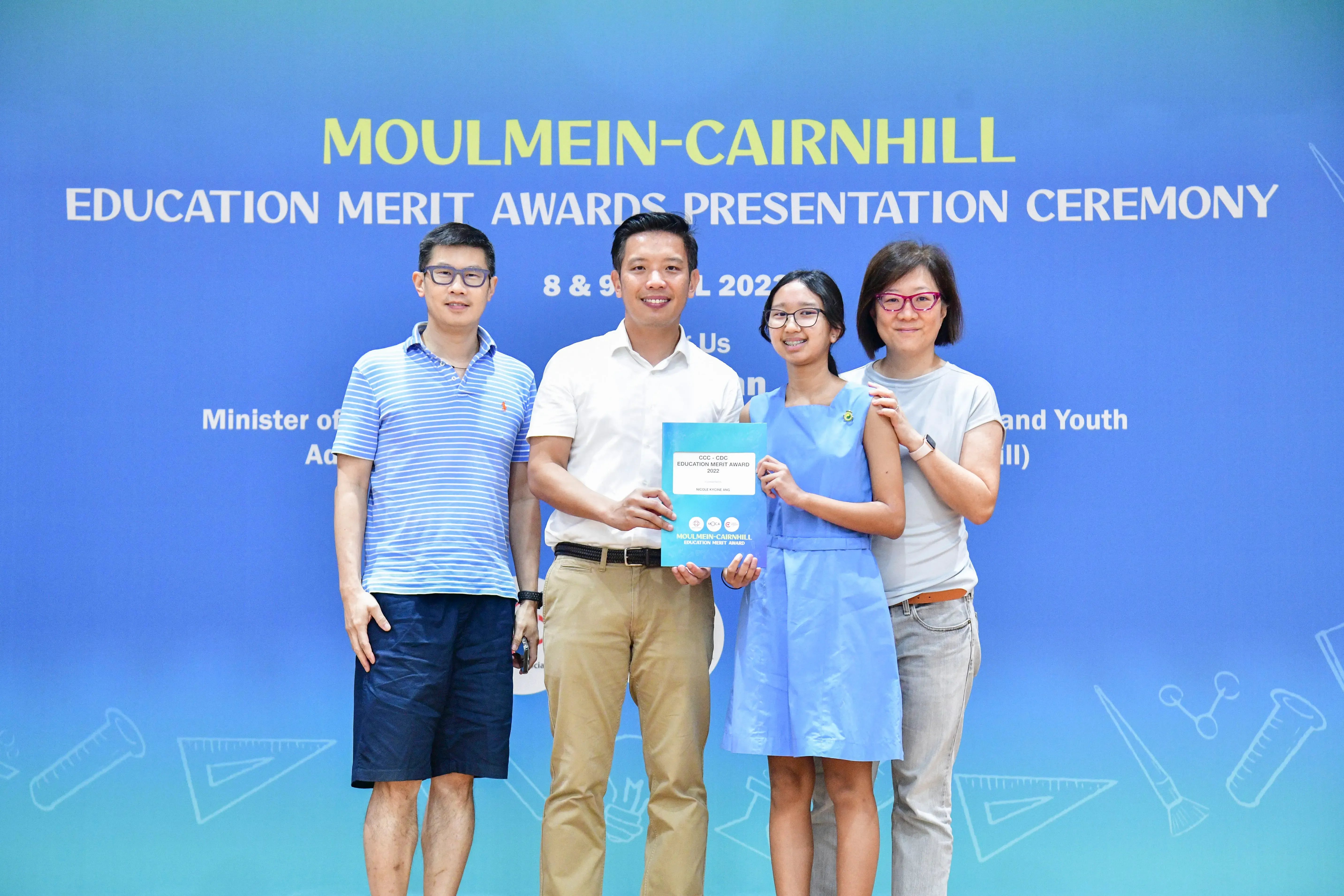 Four people pose holding a certificate at the Moulmein-Cairnhill Education Merit Awards Presentation Ceremony.