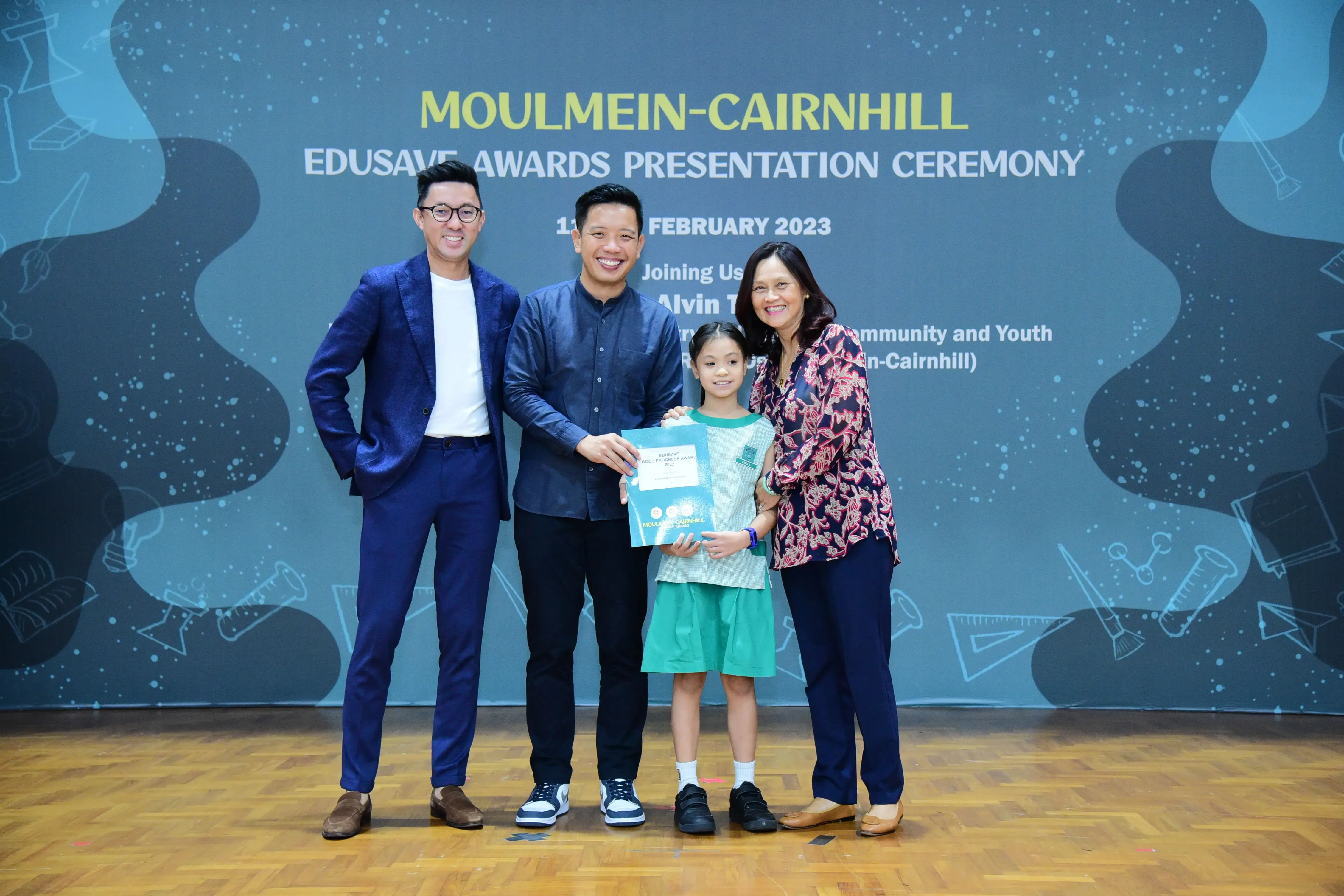 Three adults and a young girl pose with a certificate at the Moulmein-Cairnhill Edusave Awards Ceremony, February 2023.