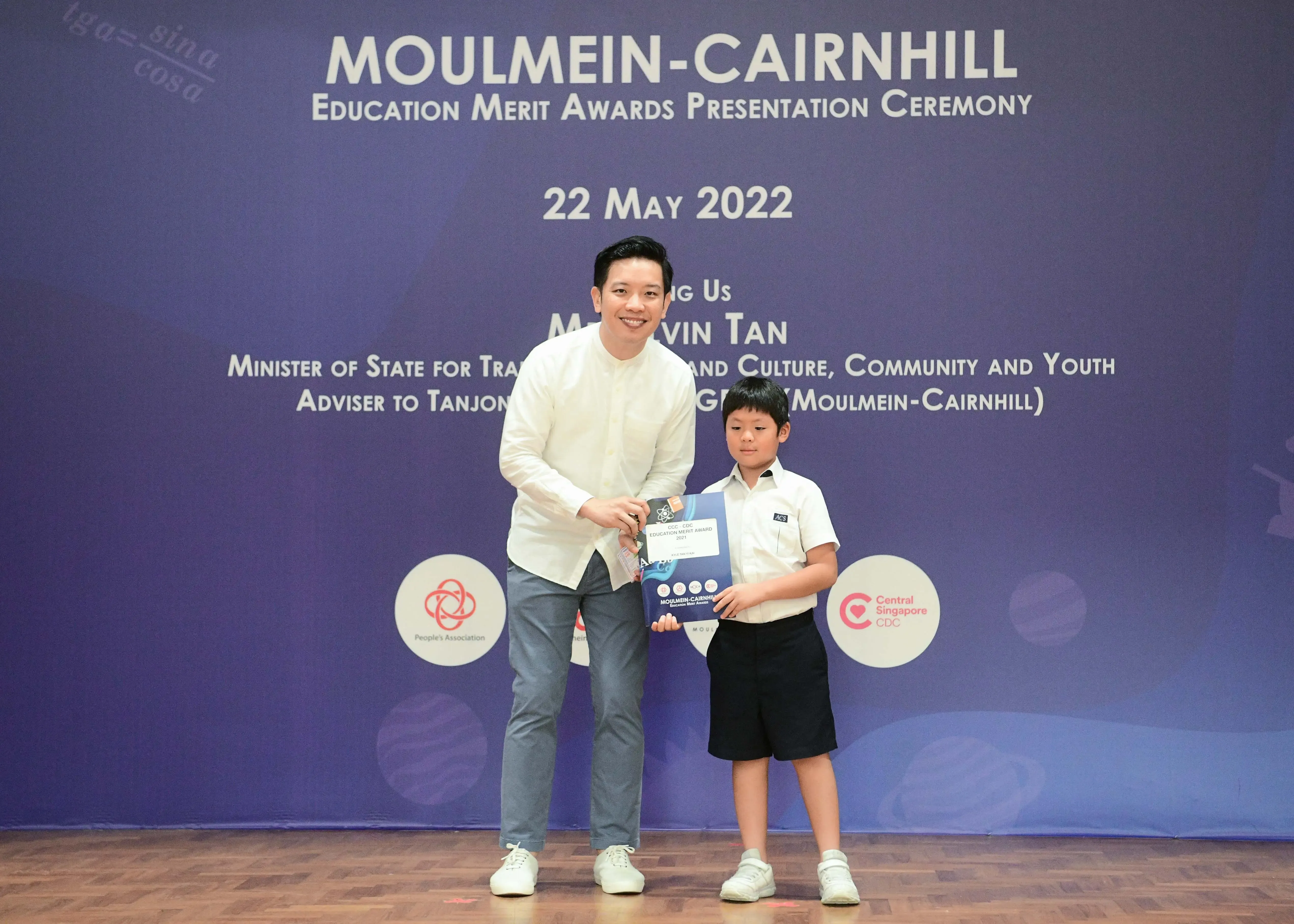 A man and a young boy hold an award certificate at the Moulmein-Cairnhill Education Merit Awards on 22 May 2022.