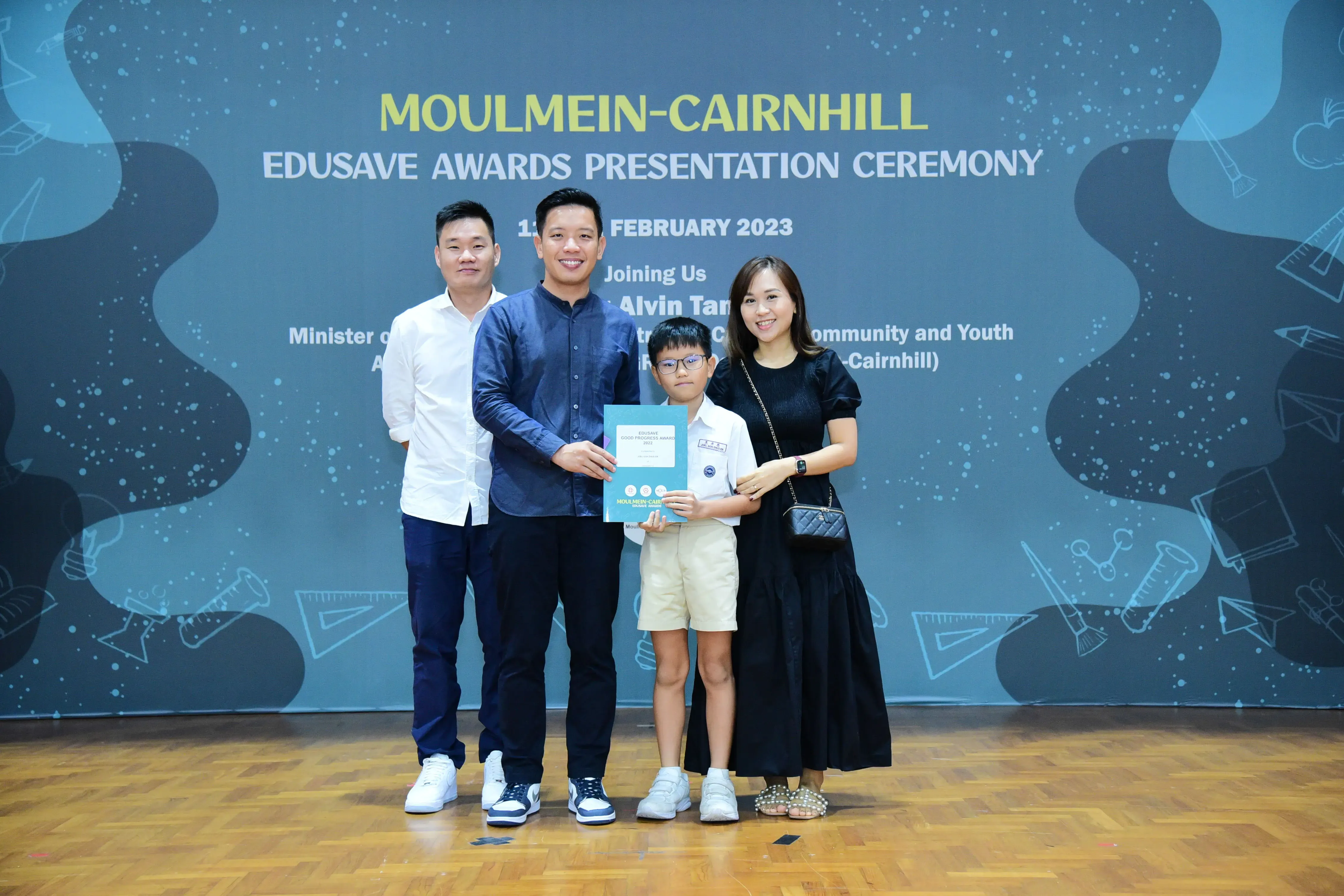 Three adults and a boy holding a certificate pose at the Moulmein-Cairnhill Edusave Awards Ceremony, February 2023.