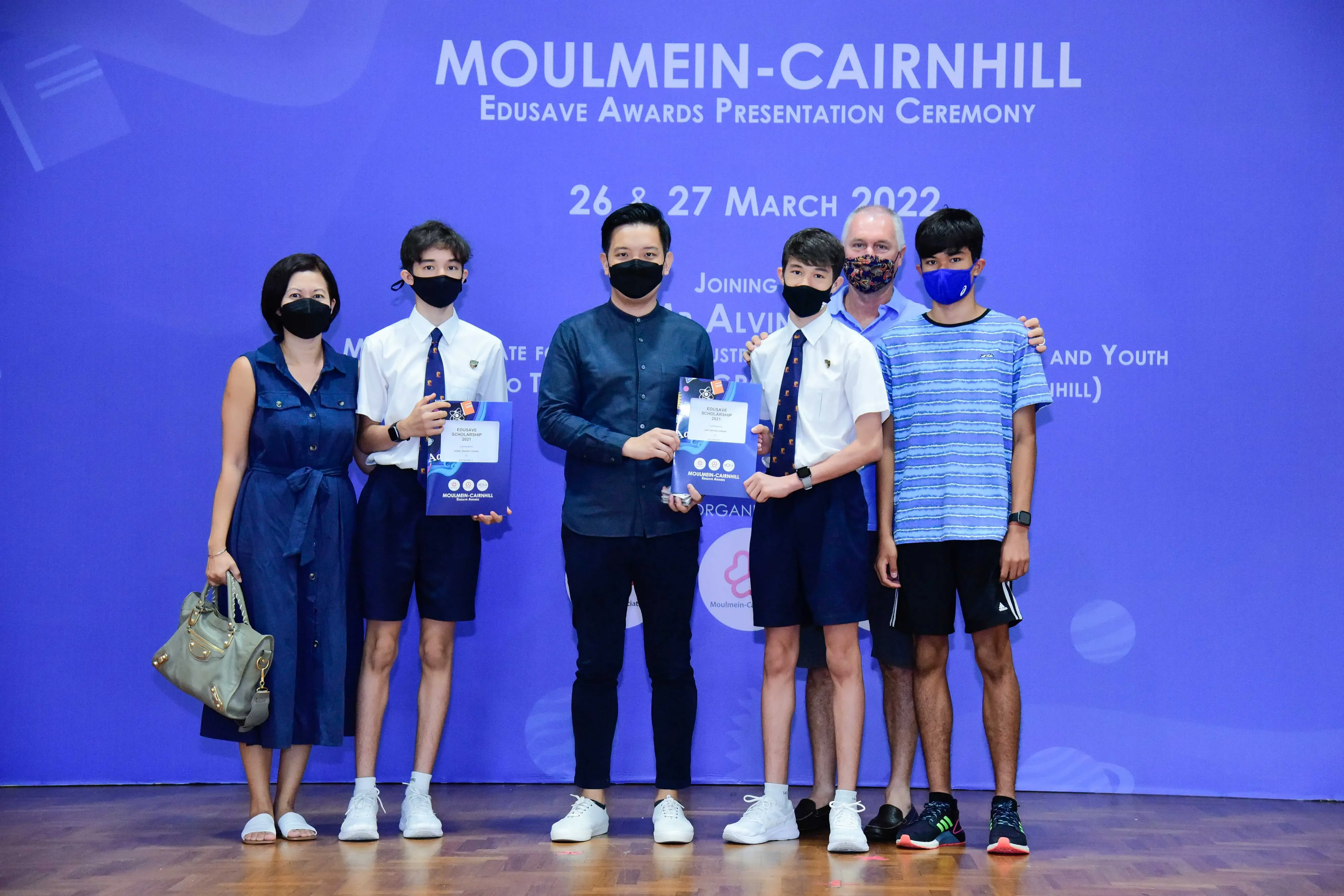 Six masked people pose at the Moulmein-Cairnhill Edusave Awards Presentation Ceremony on 26-27 March 2022.