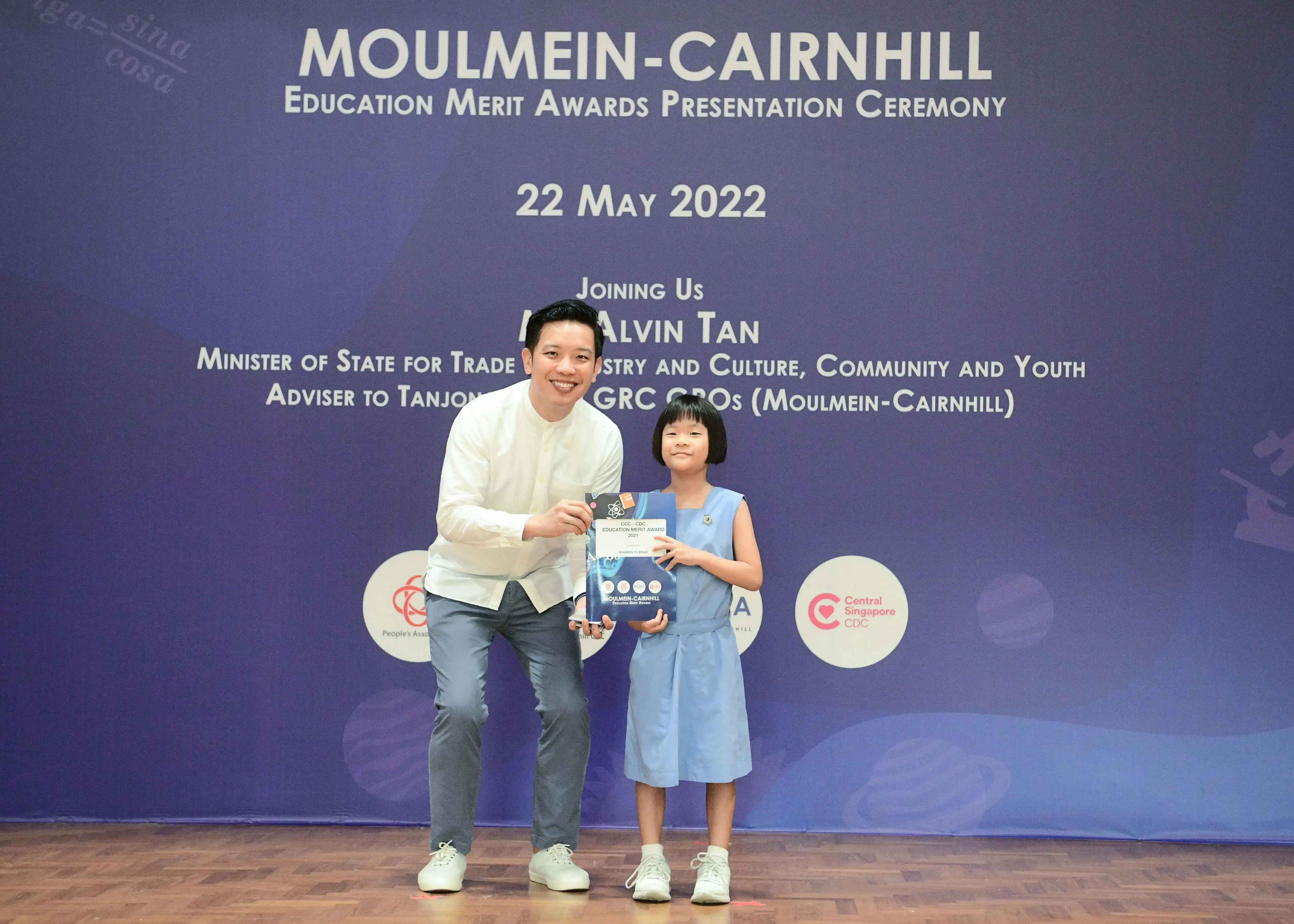 A man and a young girl hold an award at the Moulmein-Cairnhill Education Merit Awards Ceremony on 22 May 2022.