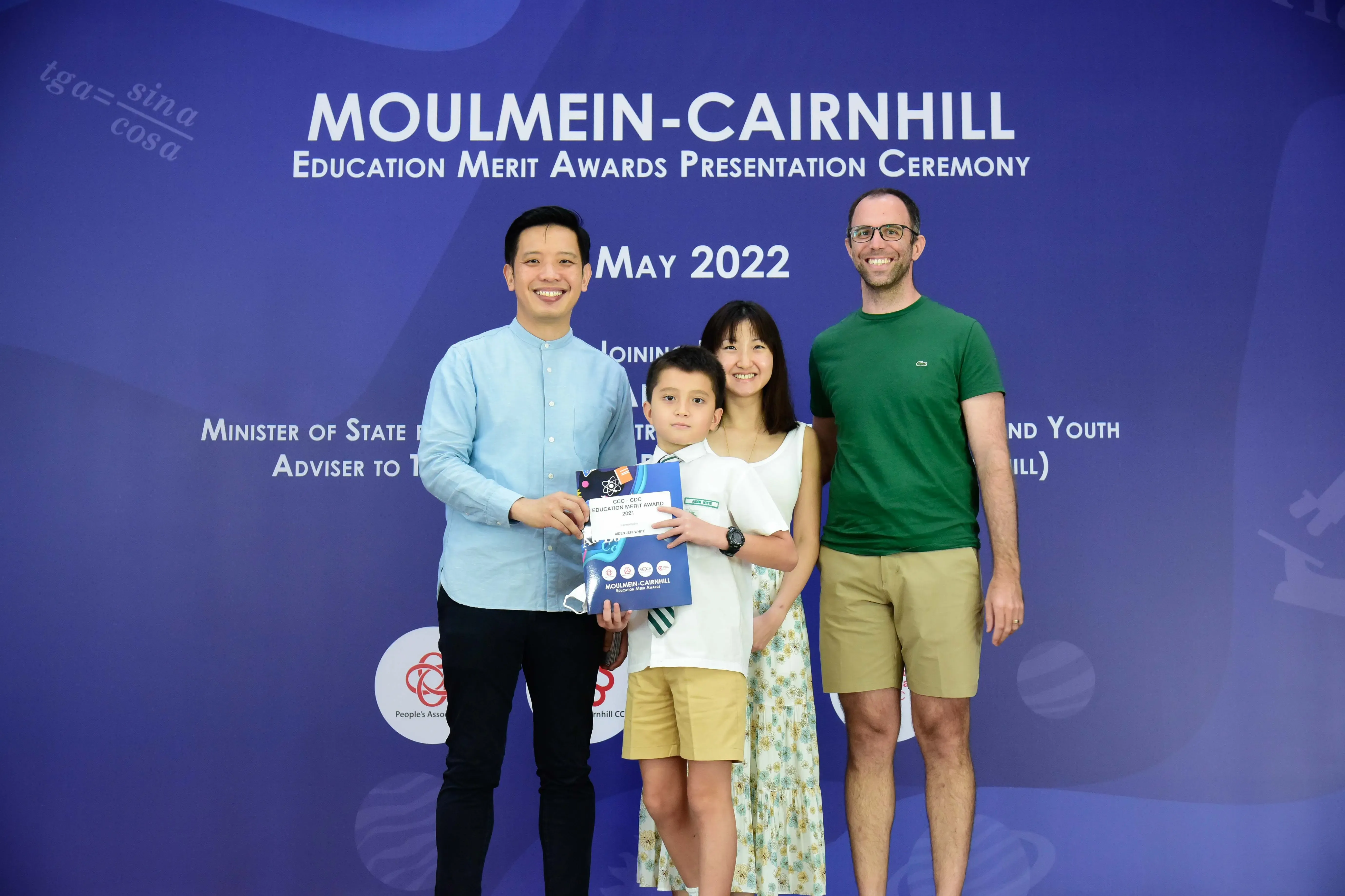 Four people pose at the Moulmein-Cairnhill Education Merit Awards Presentation Ceremony, May 2022, holding a certificate.
