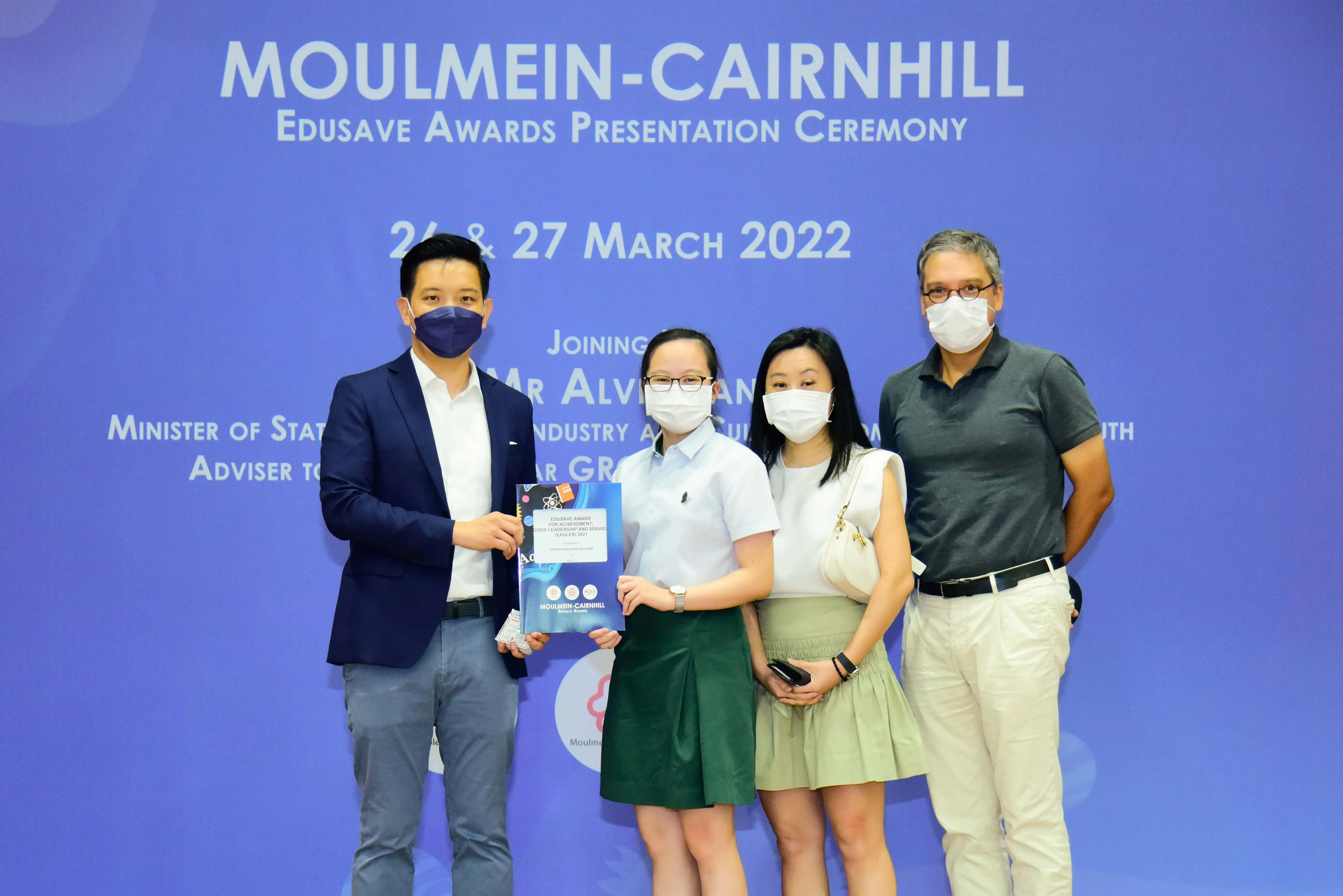 Four masked people pose at the Moulmein-Cairnhill Edusave Awards Presentation Ceremony on 26 and 27 March 2022.