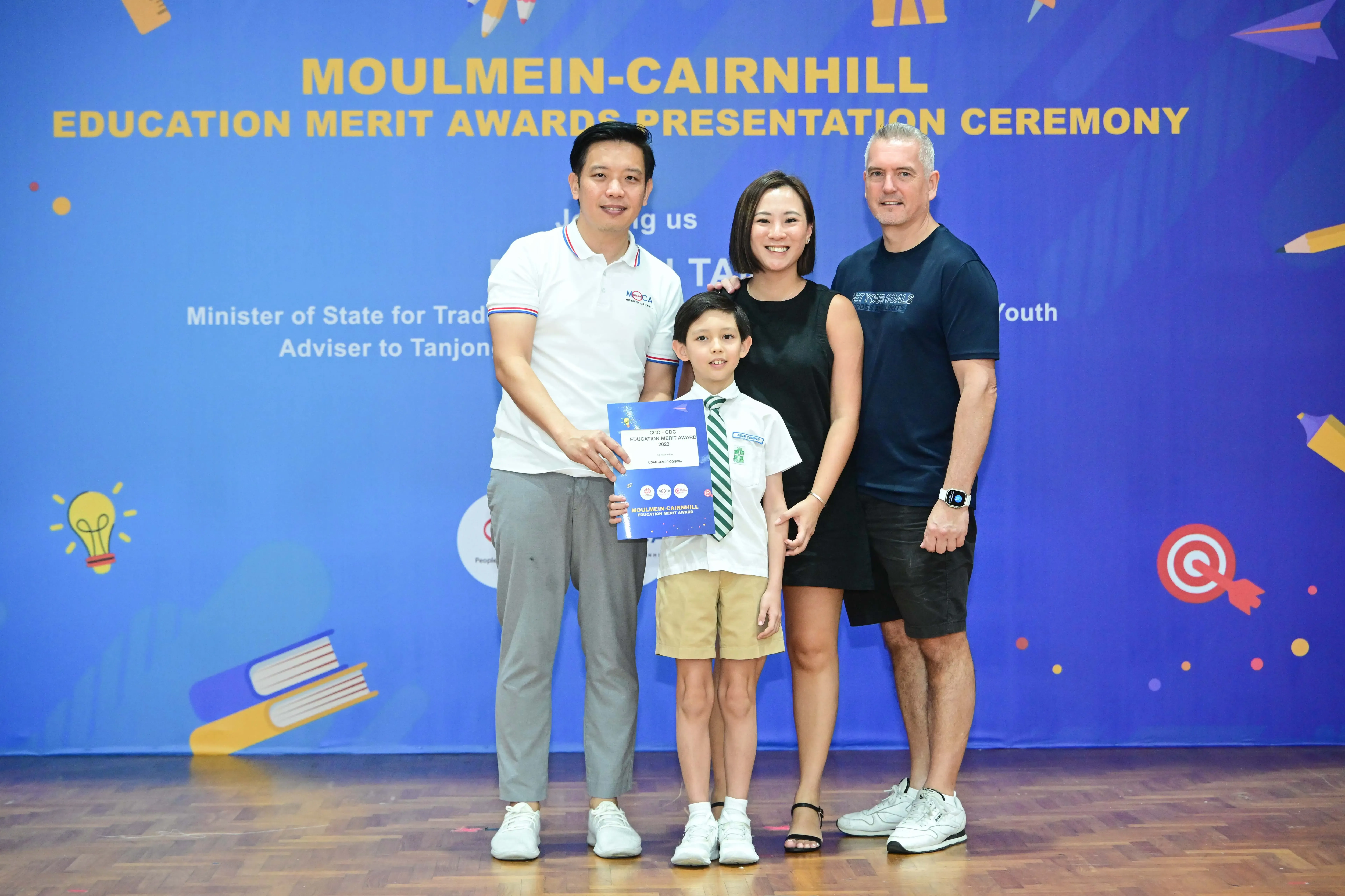 Three adults and a young boy holding a certificate pose at the Moulmein-Cairnhill Education Merit Awards Presentation Ceremony.