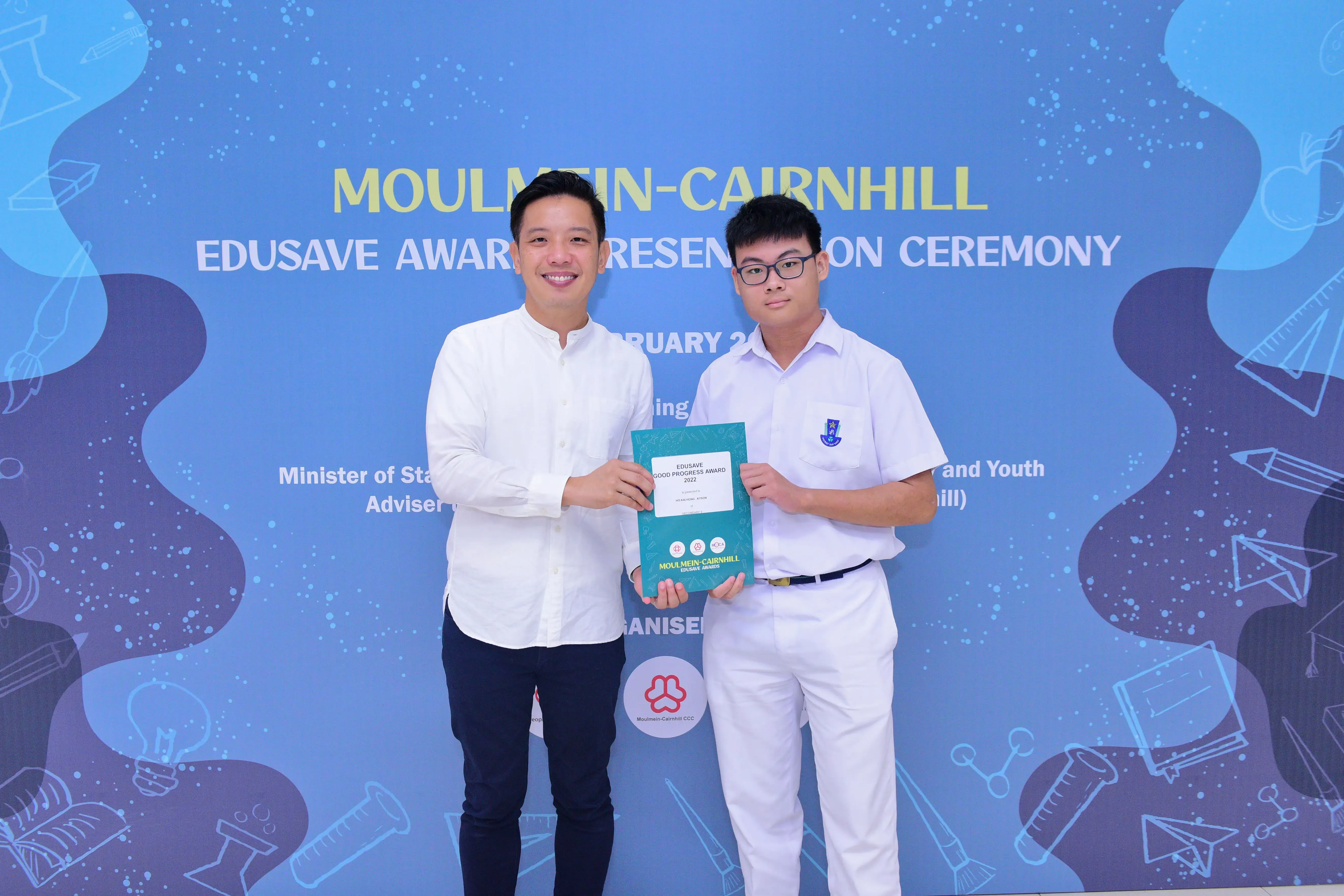 Two men hold an Edusave Good Progress Award certificate at the Moulmein-Cairnhill Edusave Award Presentation Ceremony.