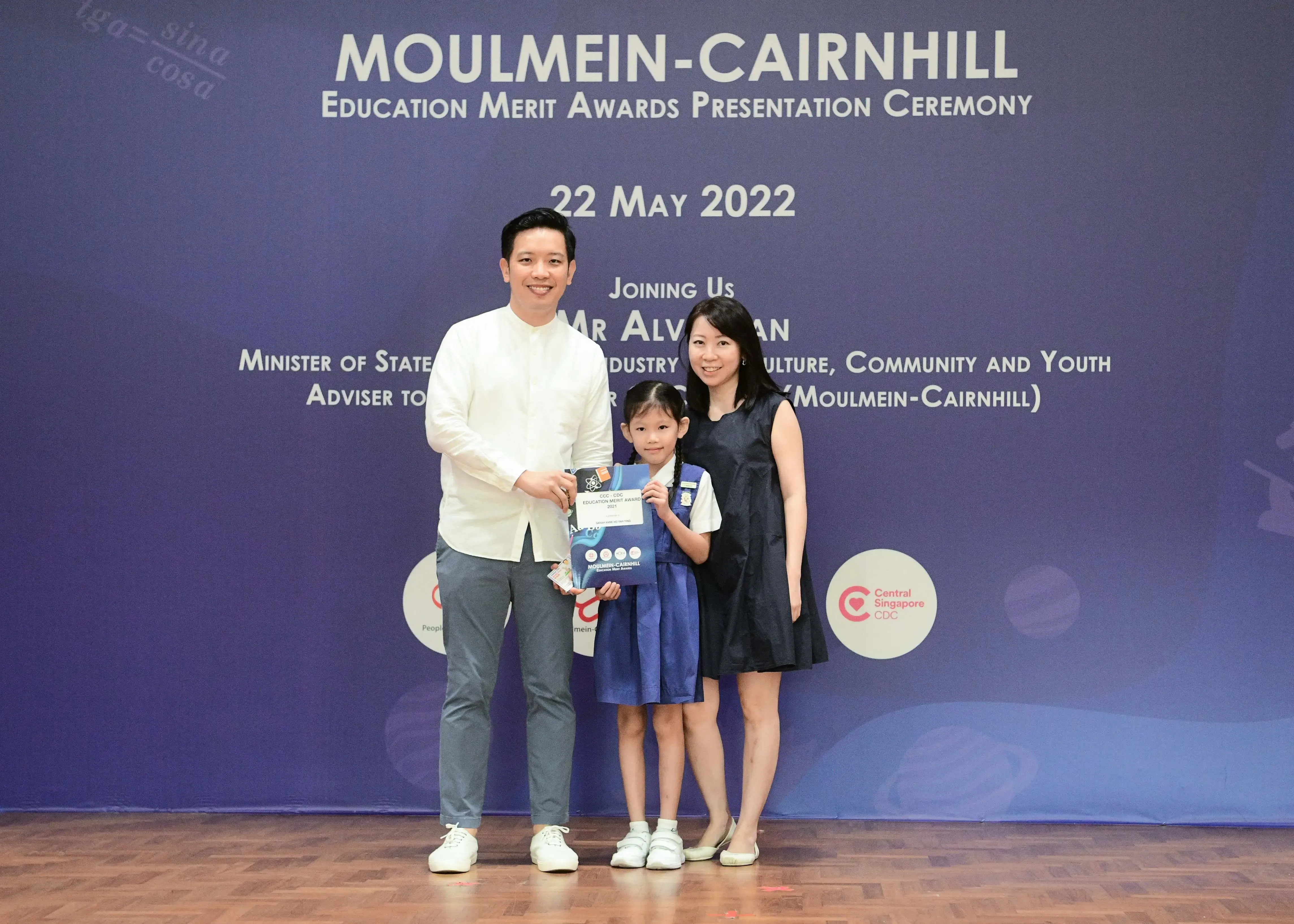 Two adults and a young girl in school uniform pose at the Moulmein-Cairnhill Education Merit Awards on 22 May 2022.
