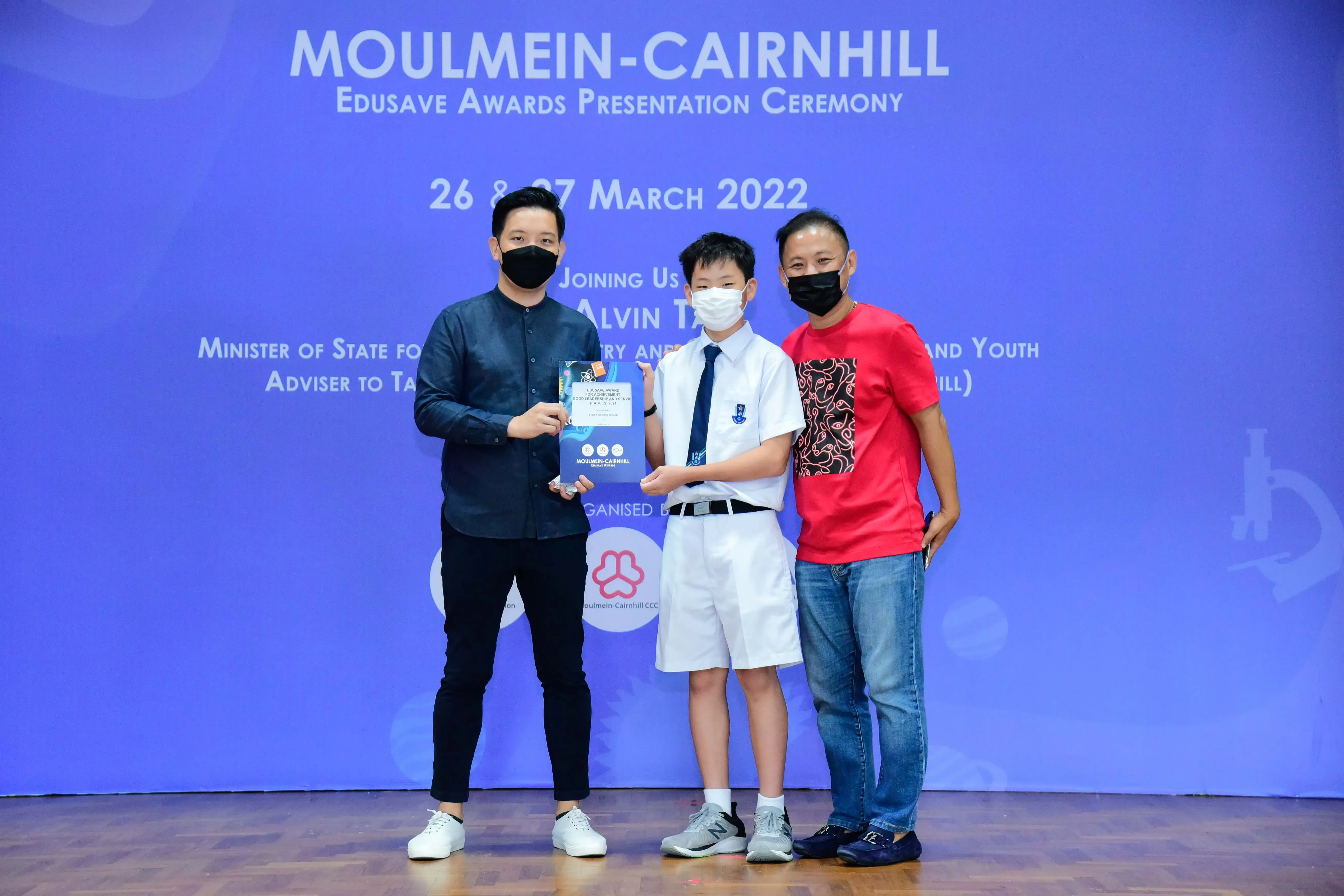 Three masked people pose at the Moulmein-Cairnhill Edusave Awards Presentation Ceremony, March 2022.
