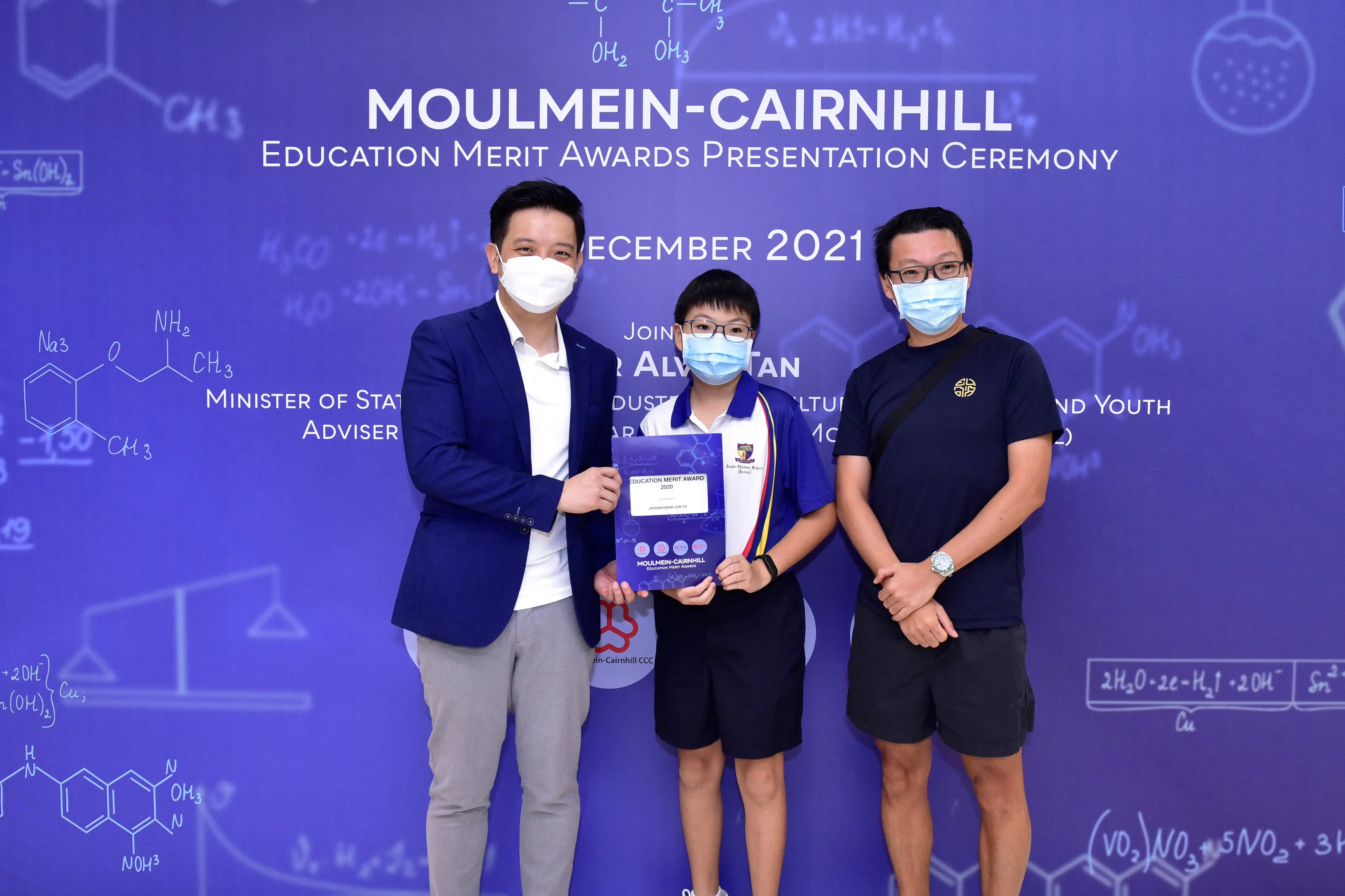Three masked people pose at the Moulmein-Cairnhill Education Merit Awards Presentation Ceremony, December 2021.