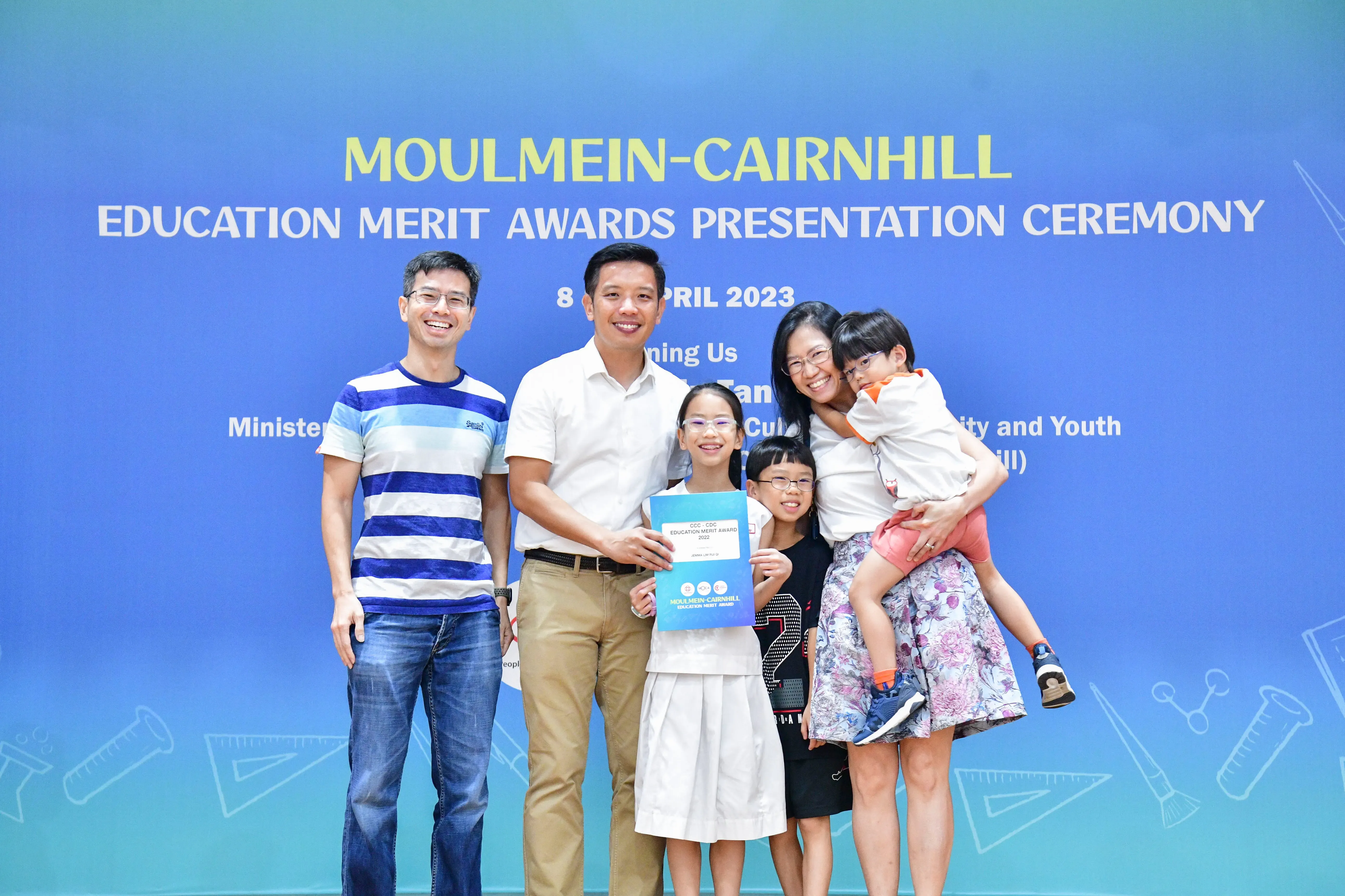 Family of five posing with an award at the Moulmein-Cairnhill Education Merit Awards Ceremony, April 2023.