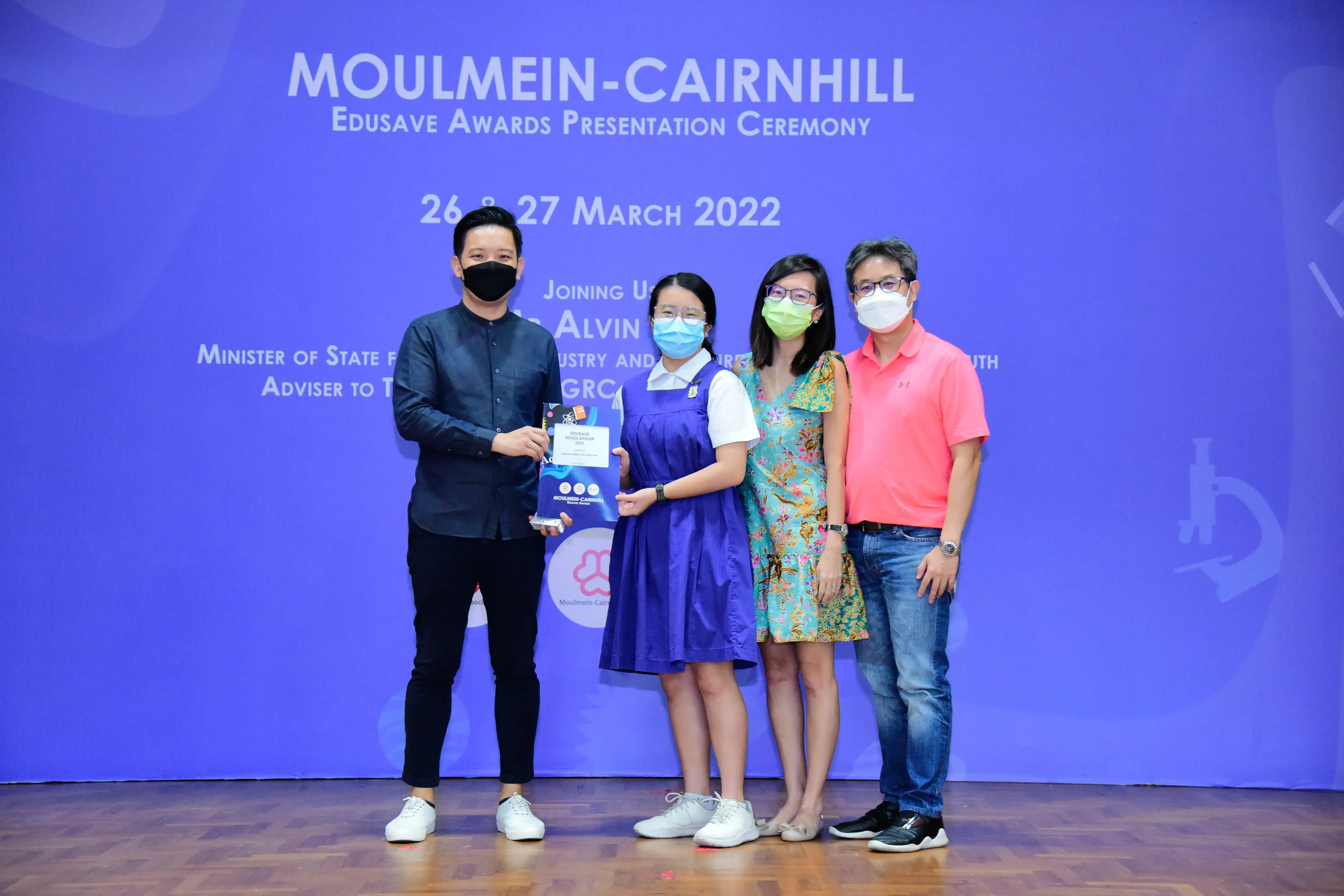 Four masked people pose at the Moulmein-Cairnhill Edusave Awards Presentation Ceremony on 26-27 March 2022.