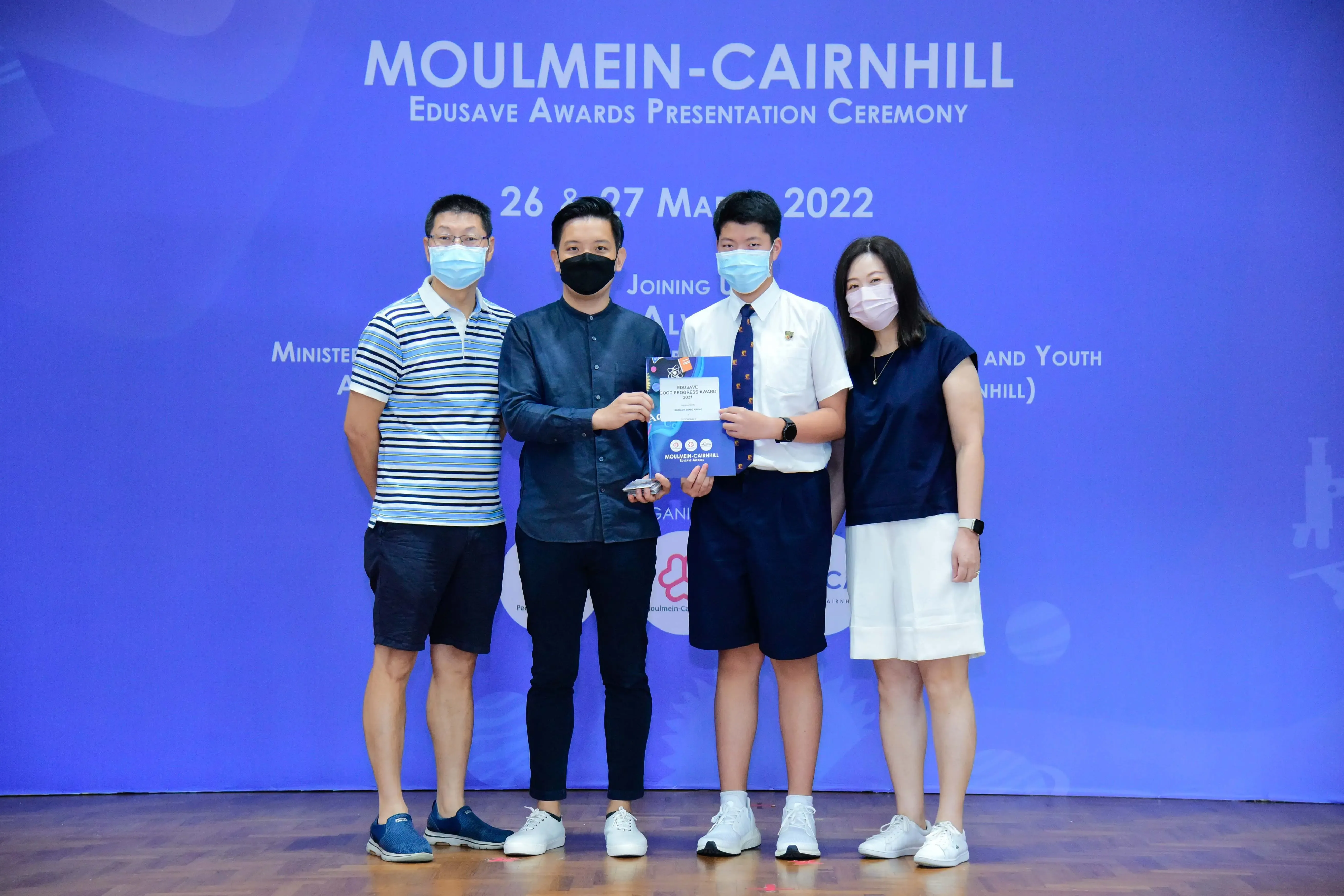 Four masked people pose at the Moulmein-Cairnhill Edusave Awards Presentation Ceremony, March 2022.