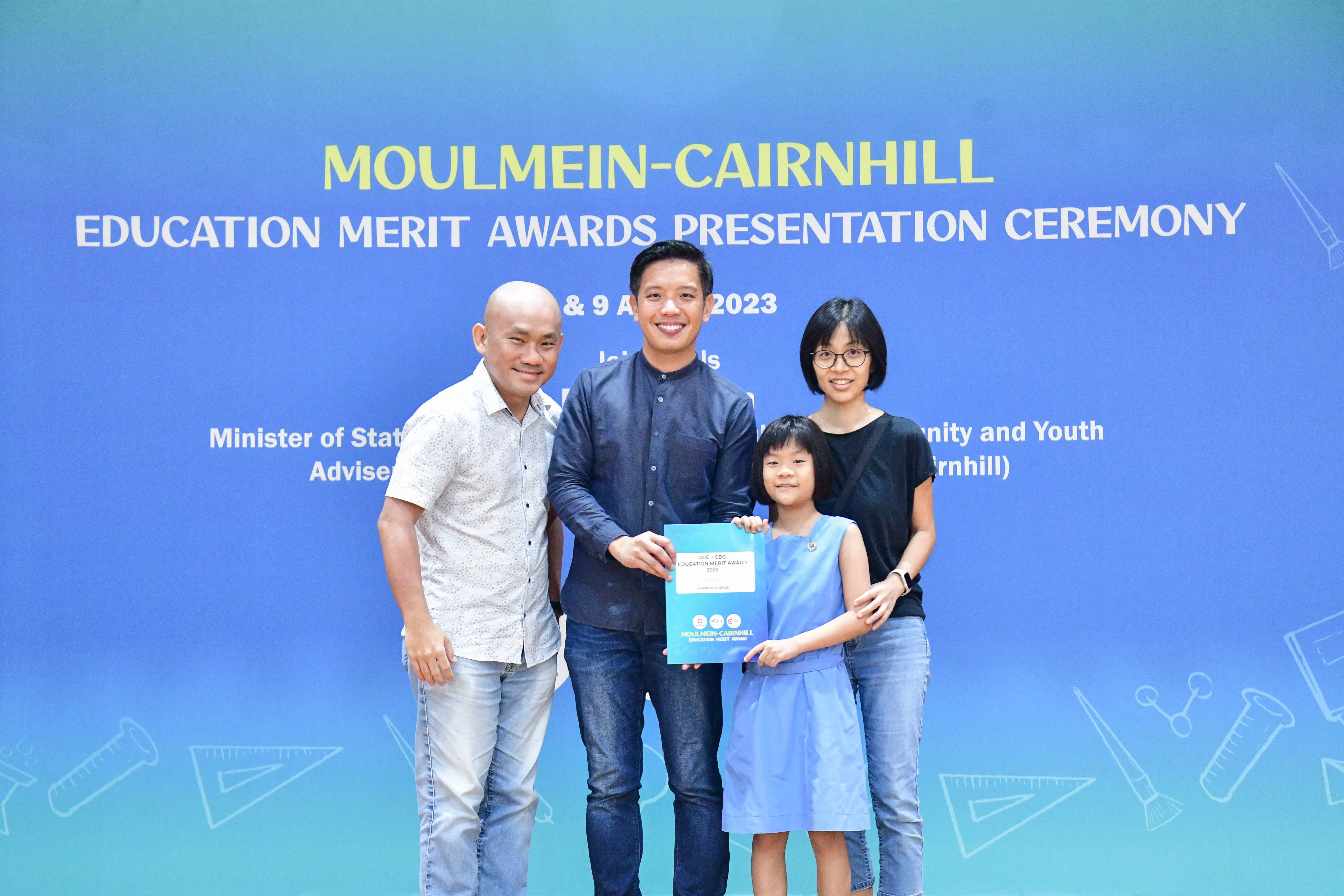 Four people pose holding an award certificate at the Moulmein-Cairnhill Education Merit Awards Presentation Ceremony 2023.