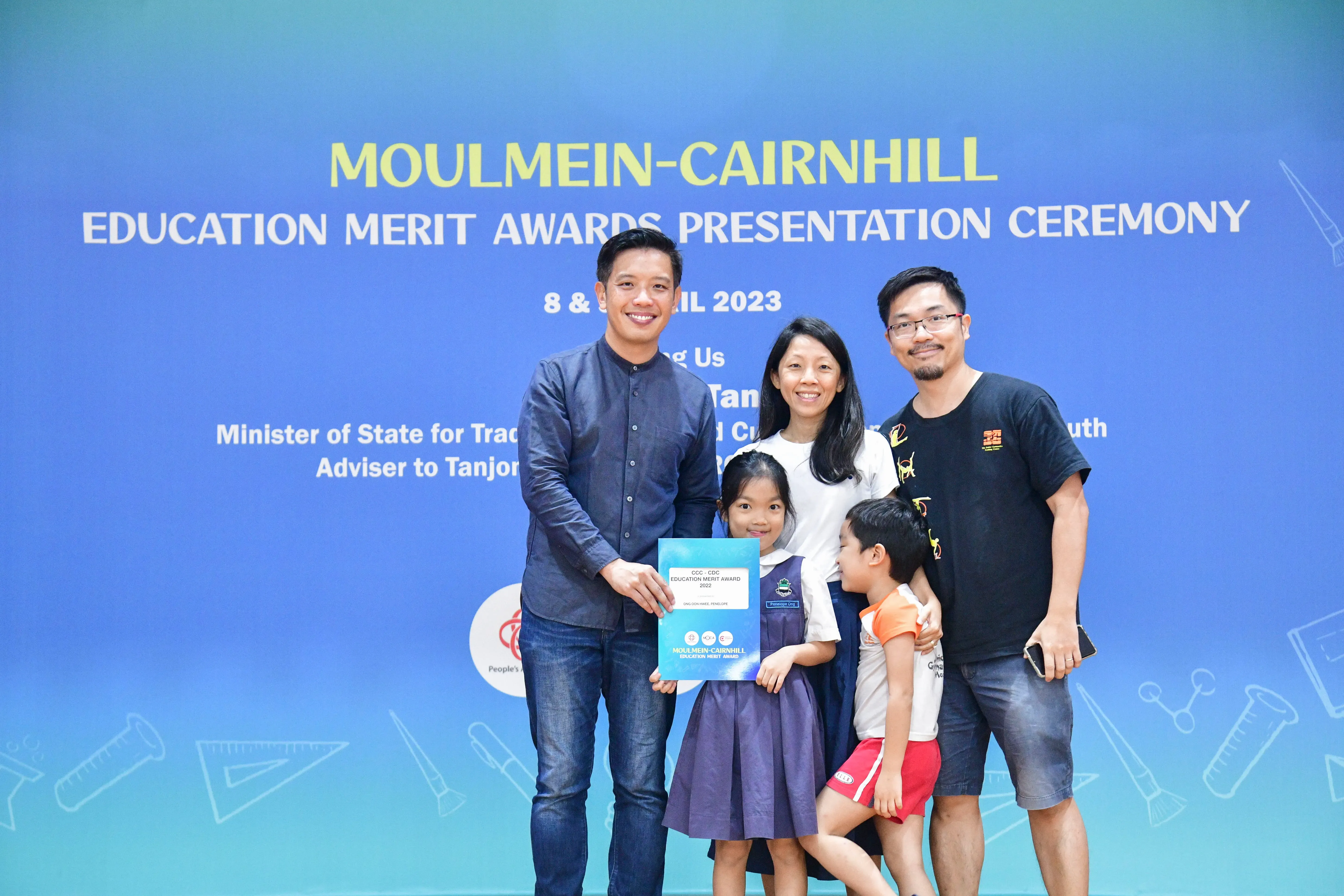 Two adults and two children pose holding an award certificate at the Moulmein-Cairnhill Education Merit Awards 2023.
