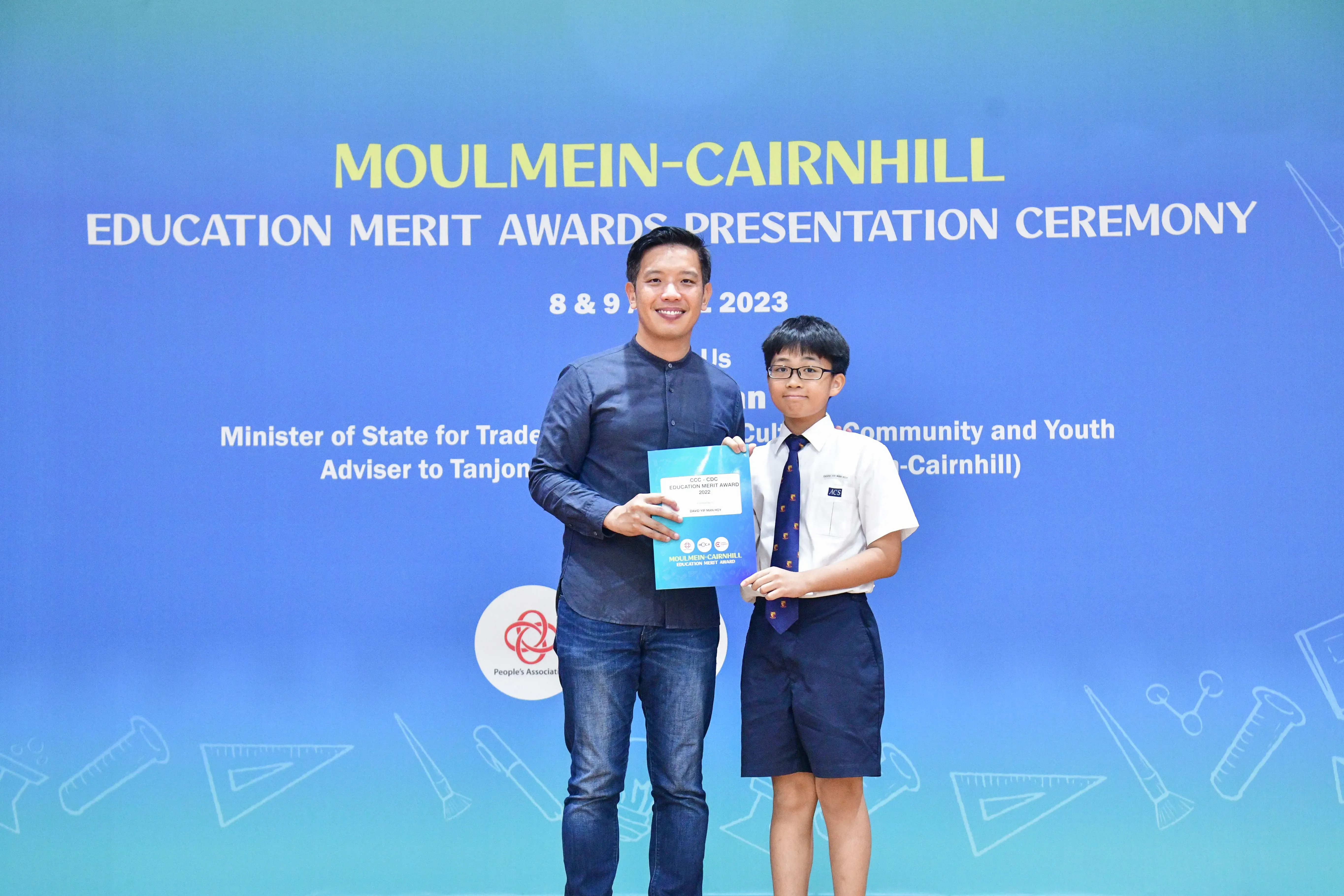 An adult and a uniformed student pose holding an award at the Moulmein-Cairnhill Education Merit Awards 2023.