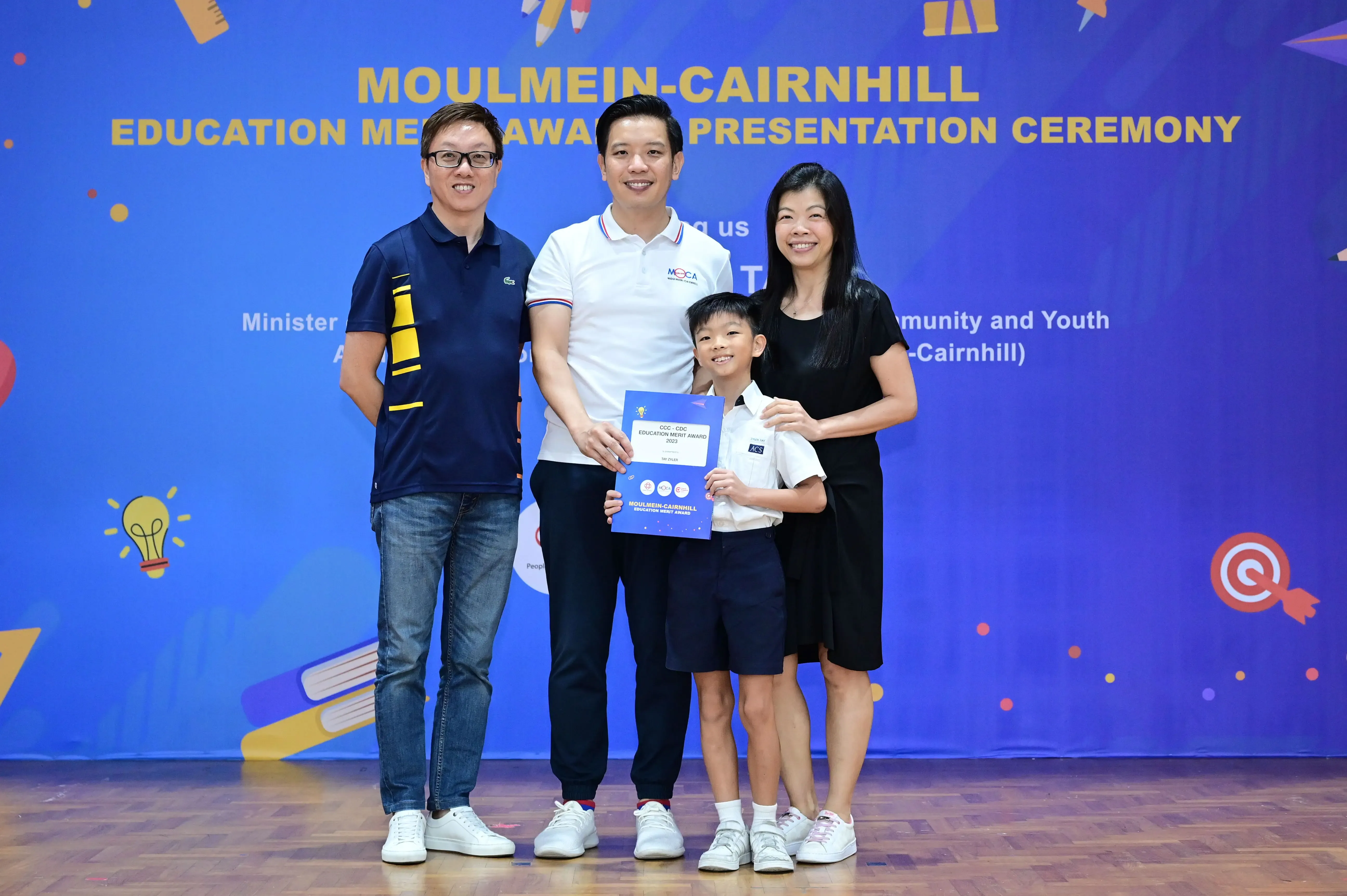 Three adults and a young boy hold a certificate at the Moulmein-Cairnhill Education Merit Award Presentation Ceremony.