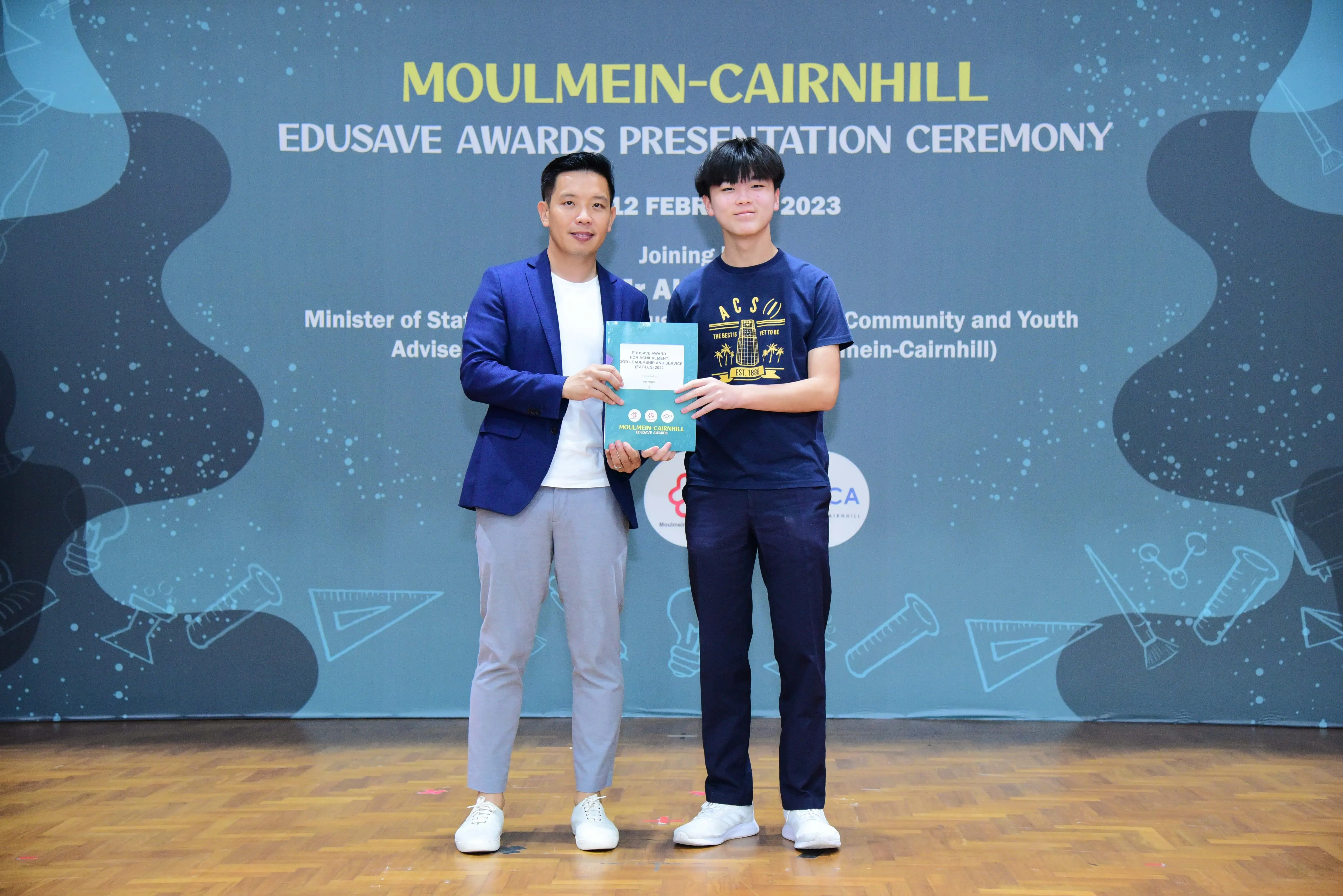 Two people hold a certificate at the Moulmein-Cairnhill Edusave Awards Presentation Ceremony on 12 February 2023.