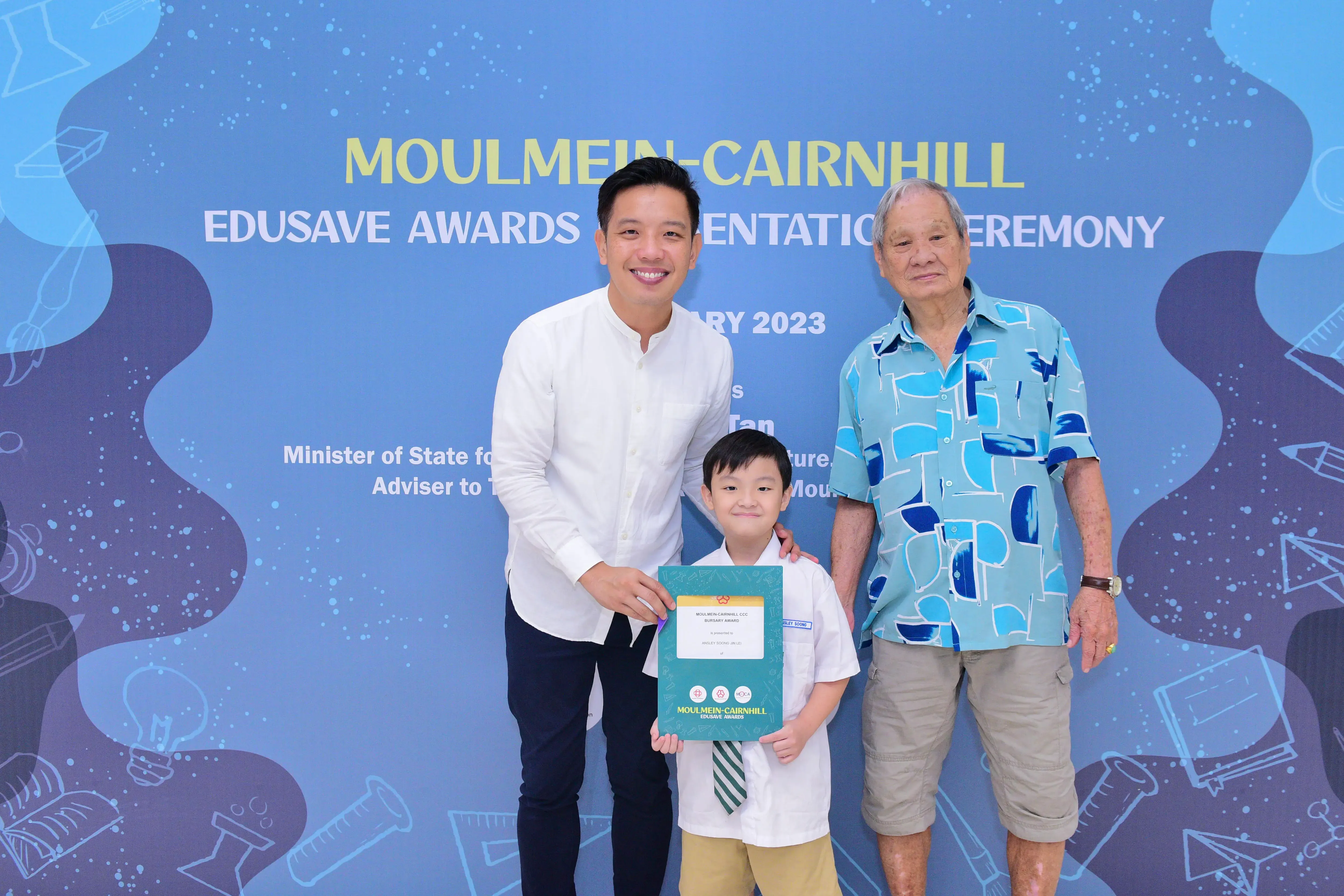 Two men and a young boy holding an award certificate at the Moulmein-Cairnhill Edusave Awards Ceremony 2023.