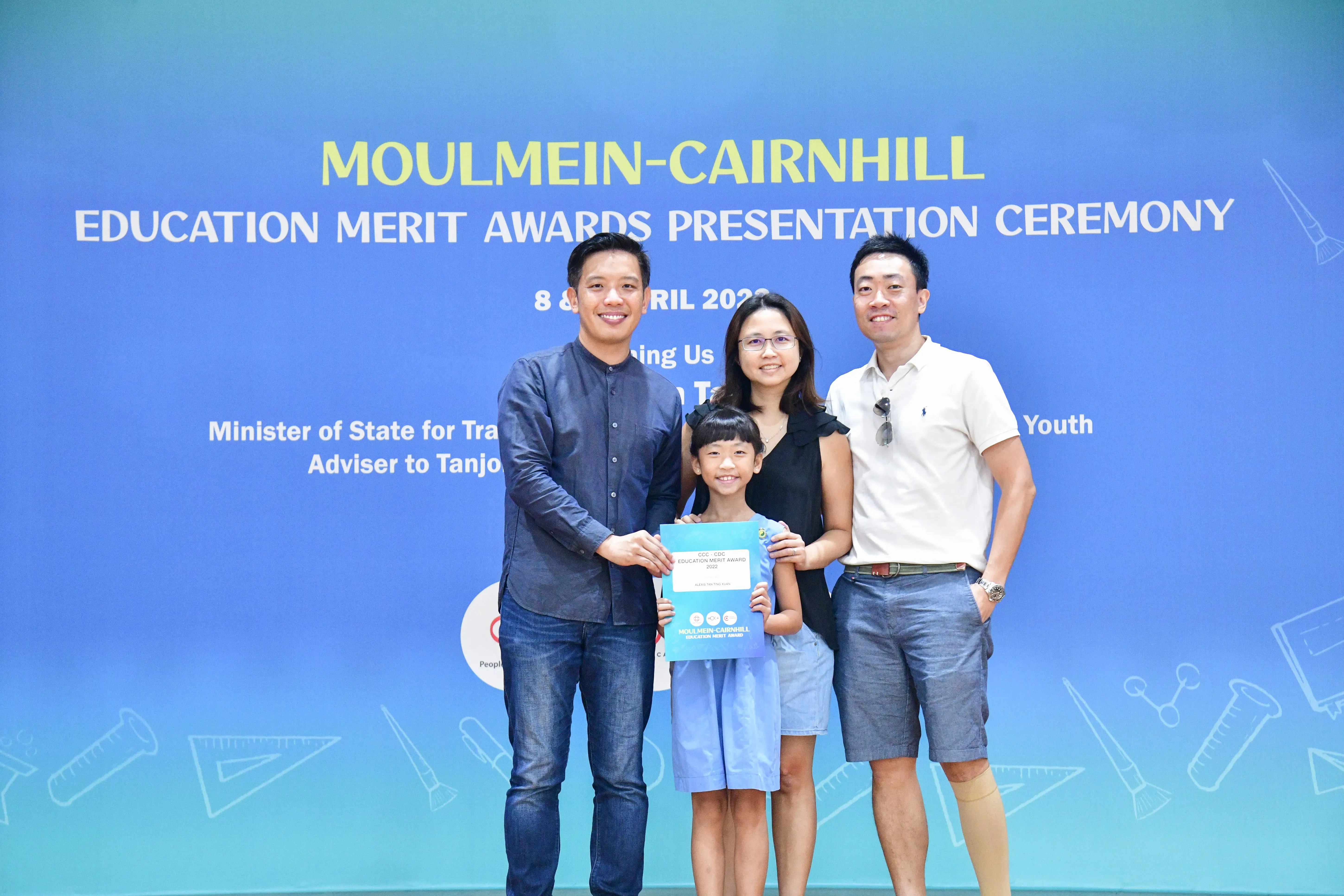 Three adults and a young girl pose with a certificate at the Moulmein-Cairnhill Education Merit Awards Ceremony.