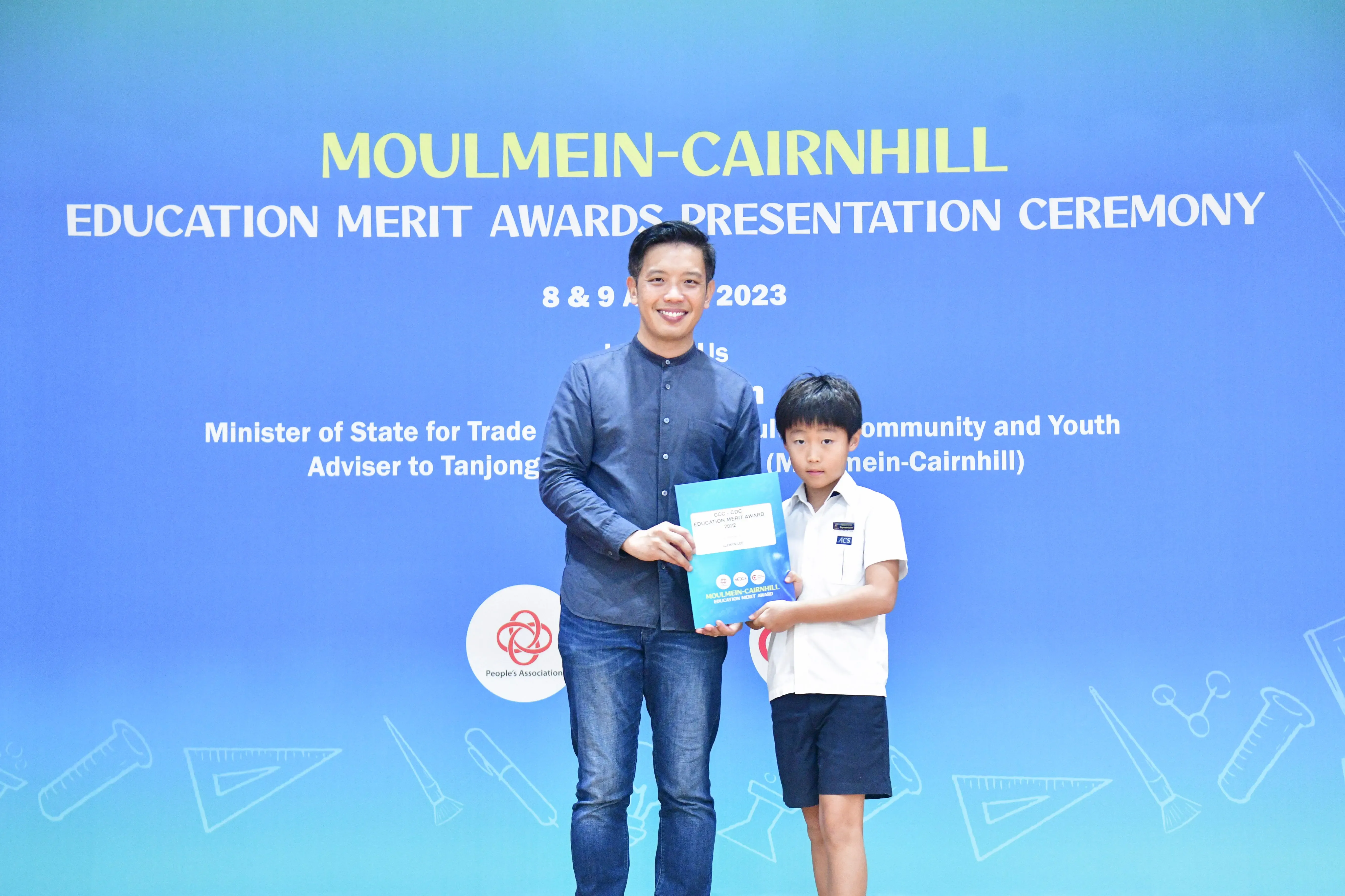 A man and a young boy hold an award certificate together at the Moulmein-Cairnhill Education Merit Awards 2023.