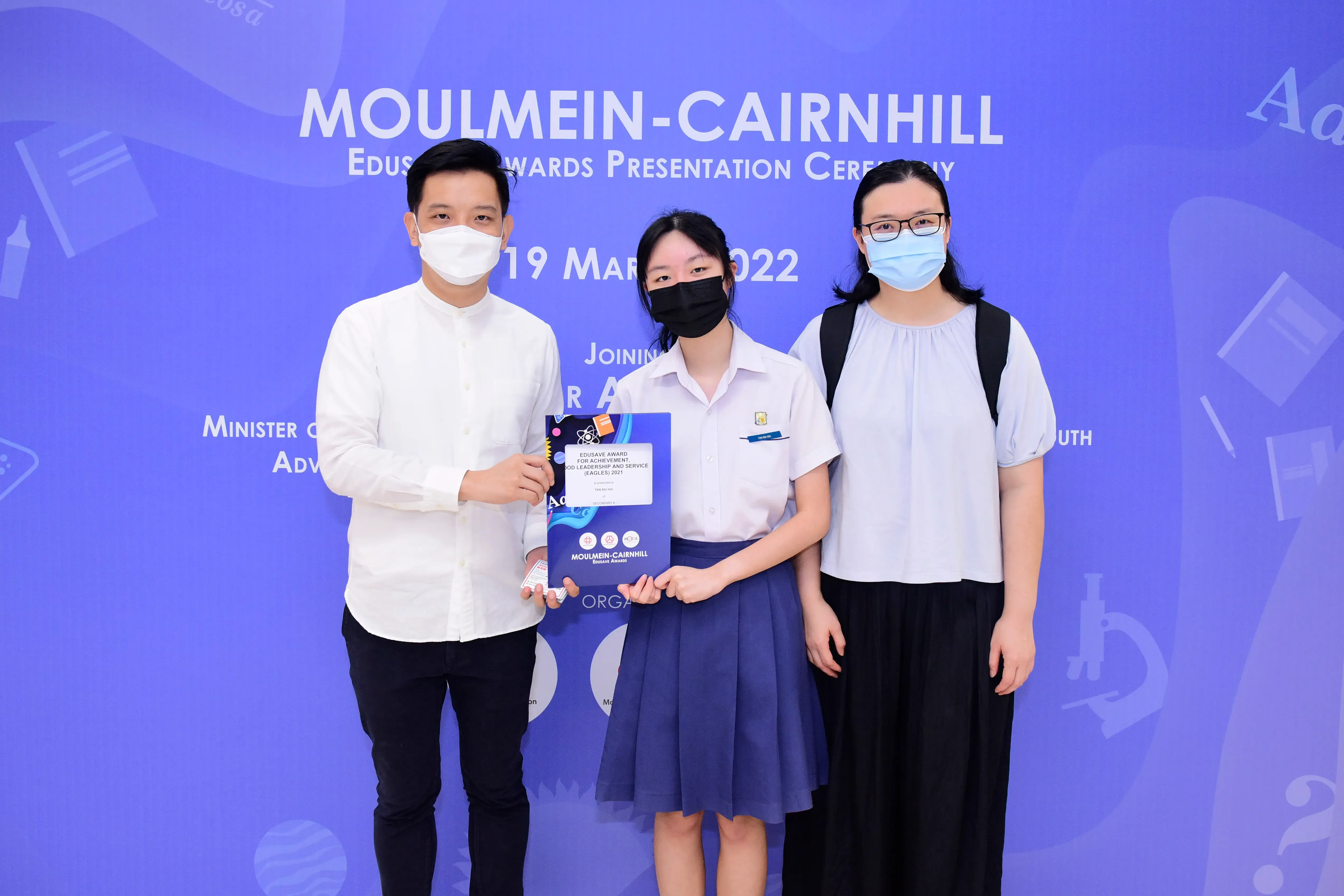 Three masked people pose at the Moulmein-Cairnhill Edusave Awards Presentation Ceremony on 19 March 2022.