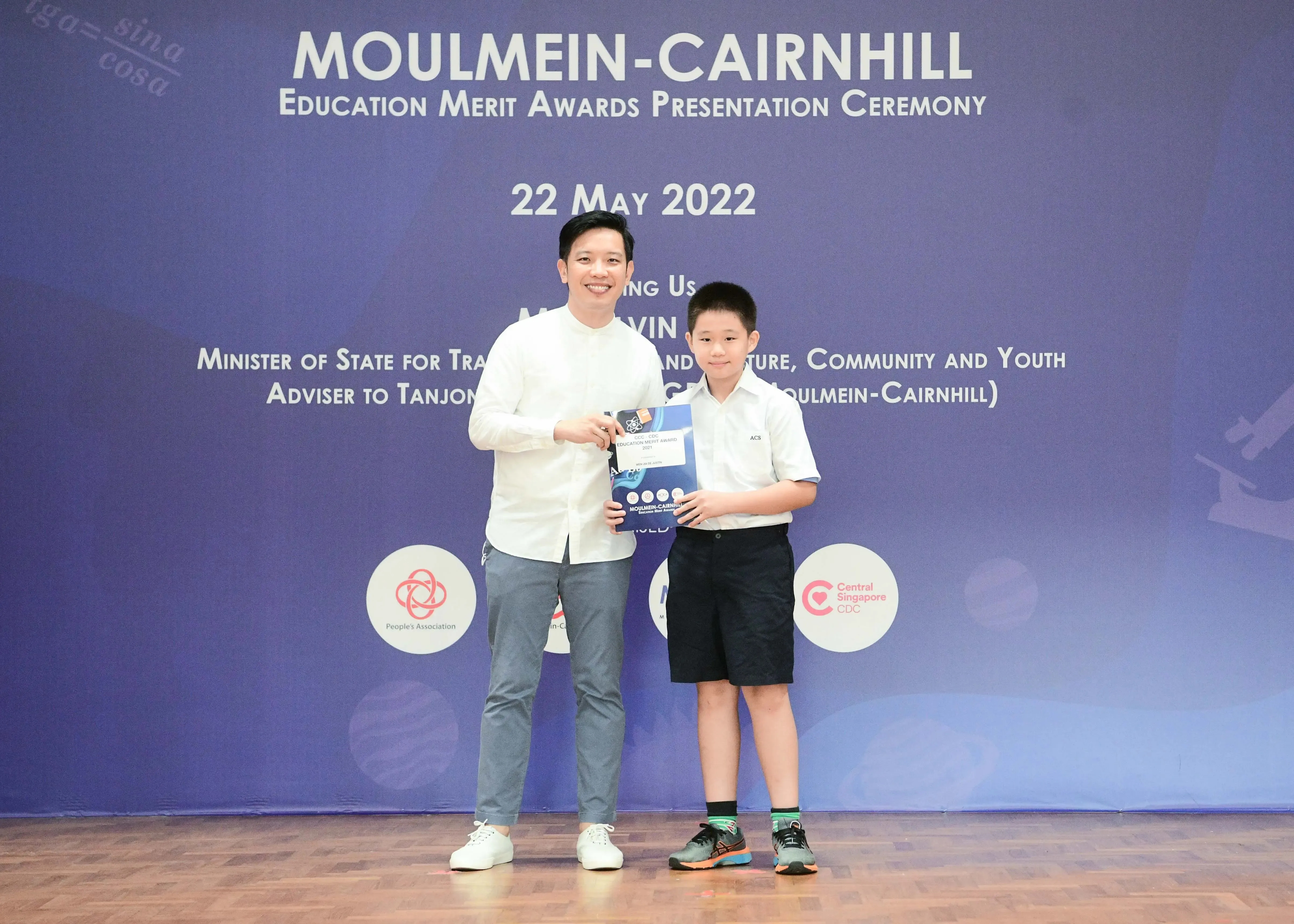 A man and a young boy pose together holding an award at the Moulmein-Cairnhill Education Merit Awards on 22 May 2022.