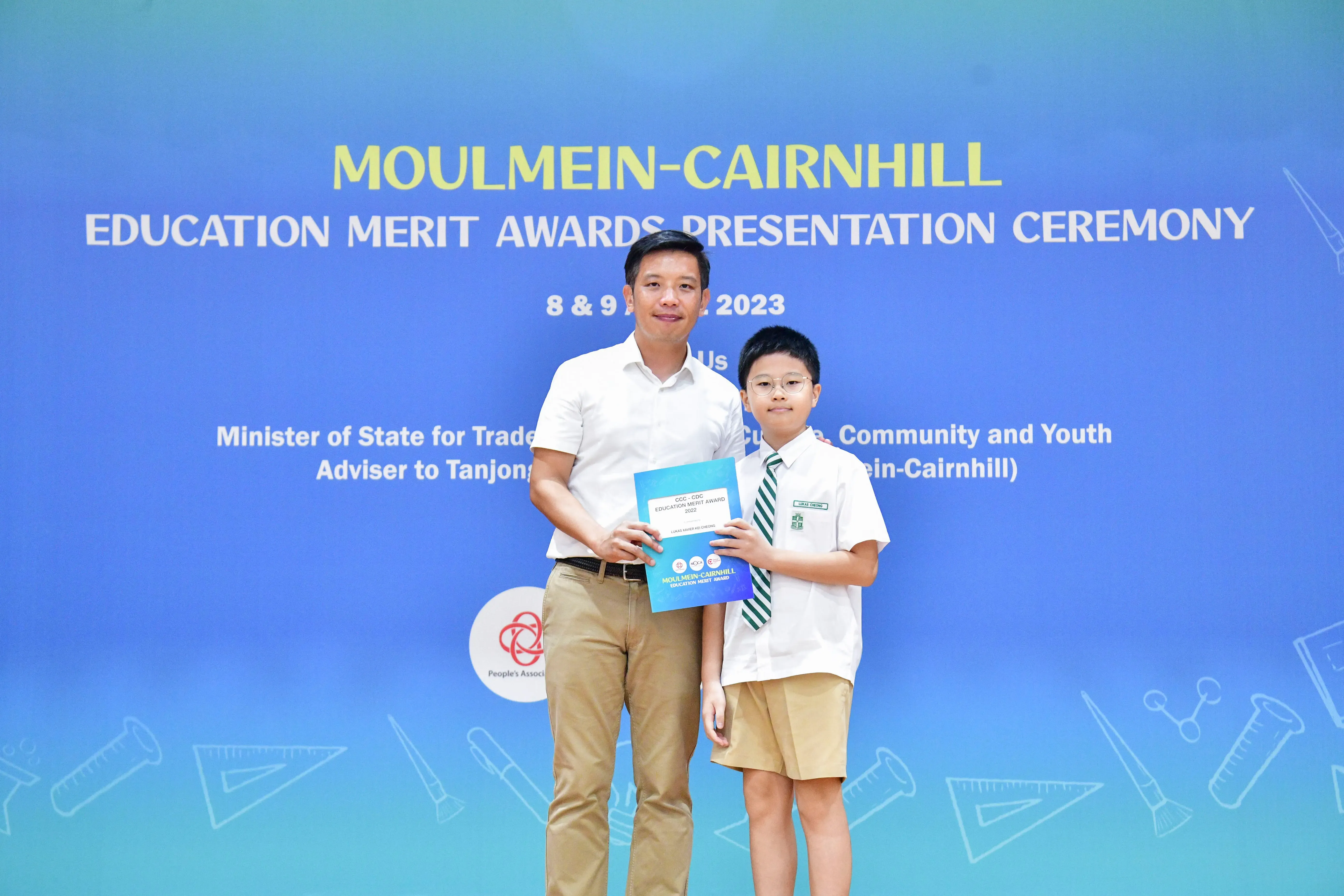 An adult and a young student pose together holding an award at the Moulmein-Cairnhill Education Merit Awards 2023.