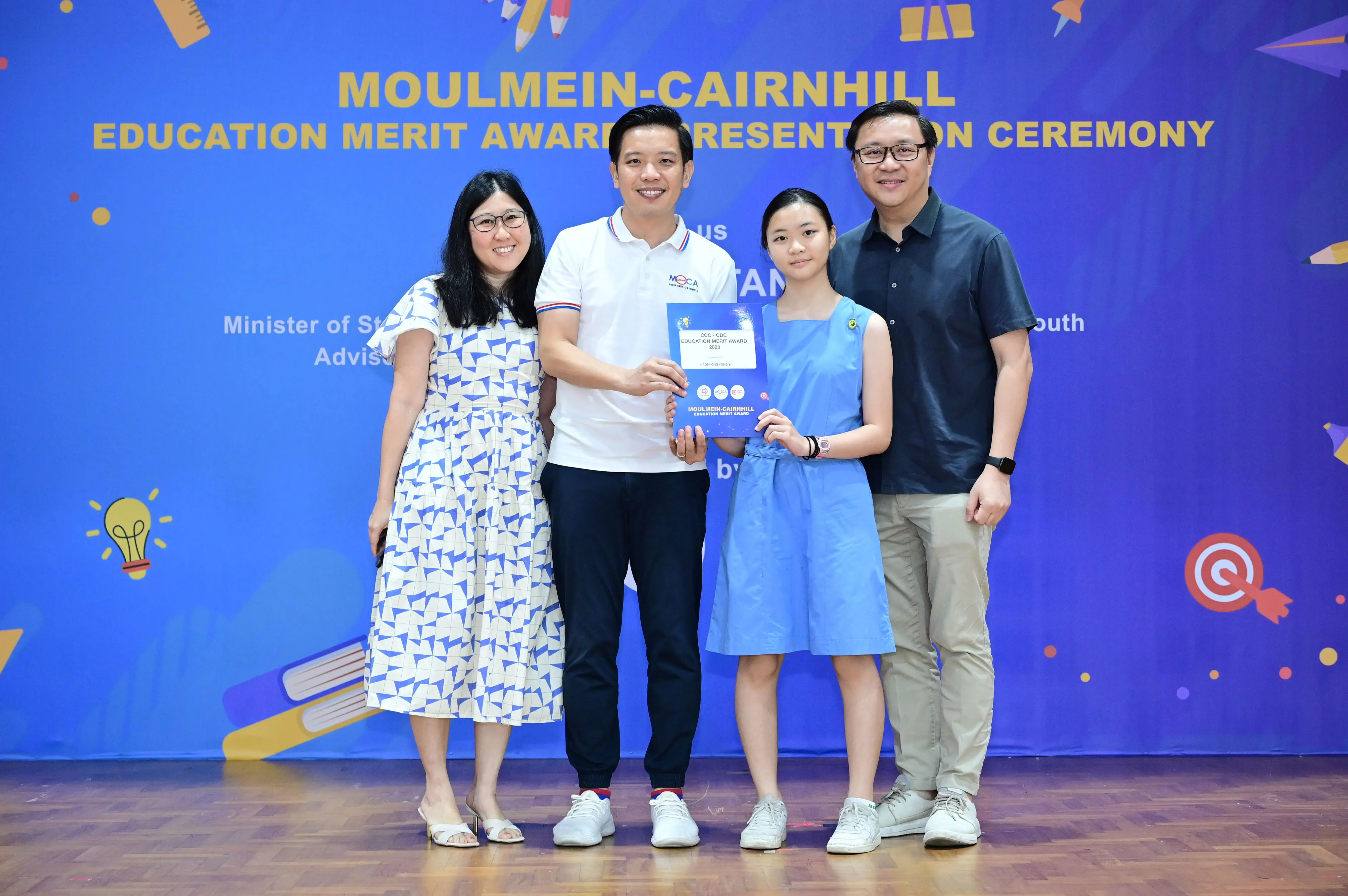 Four people posing with a certificate at the Moulmein-Cairnhill Education Merit Award Presentation Ceremony.