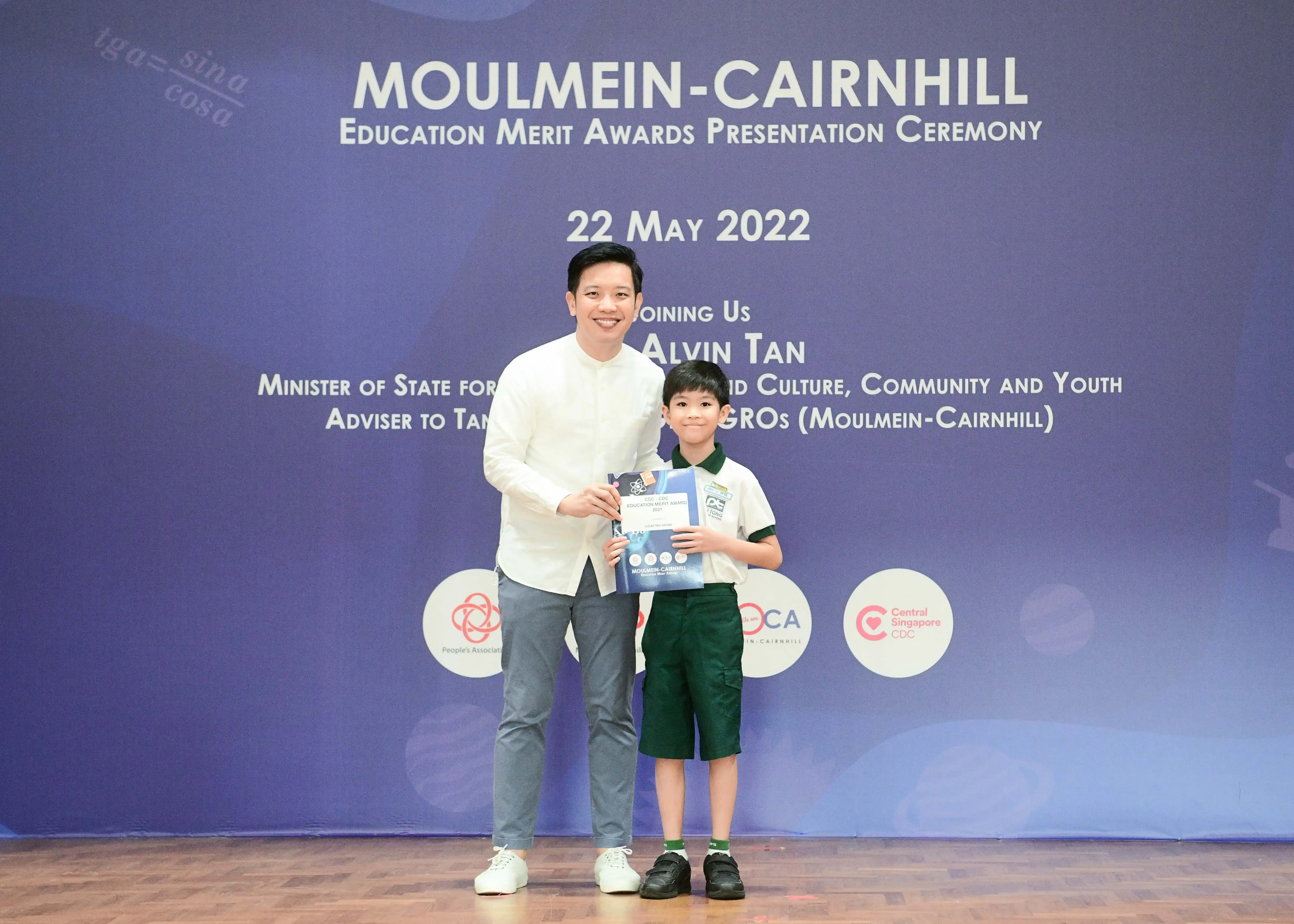 A man and a young boy hold an award certificate at the Moulmein-Cairnhill Education Merit Awards Ceremony on 22 May 2022.