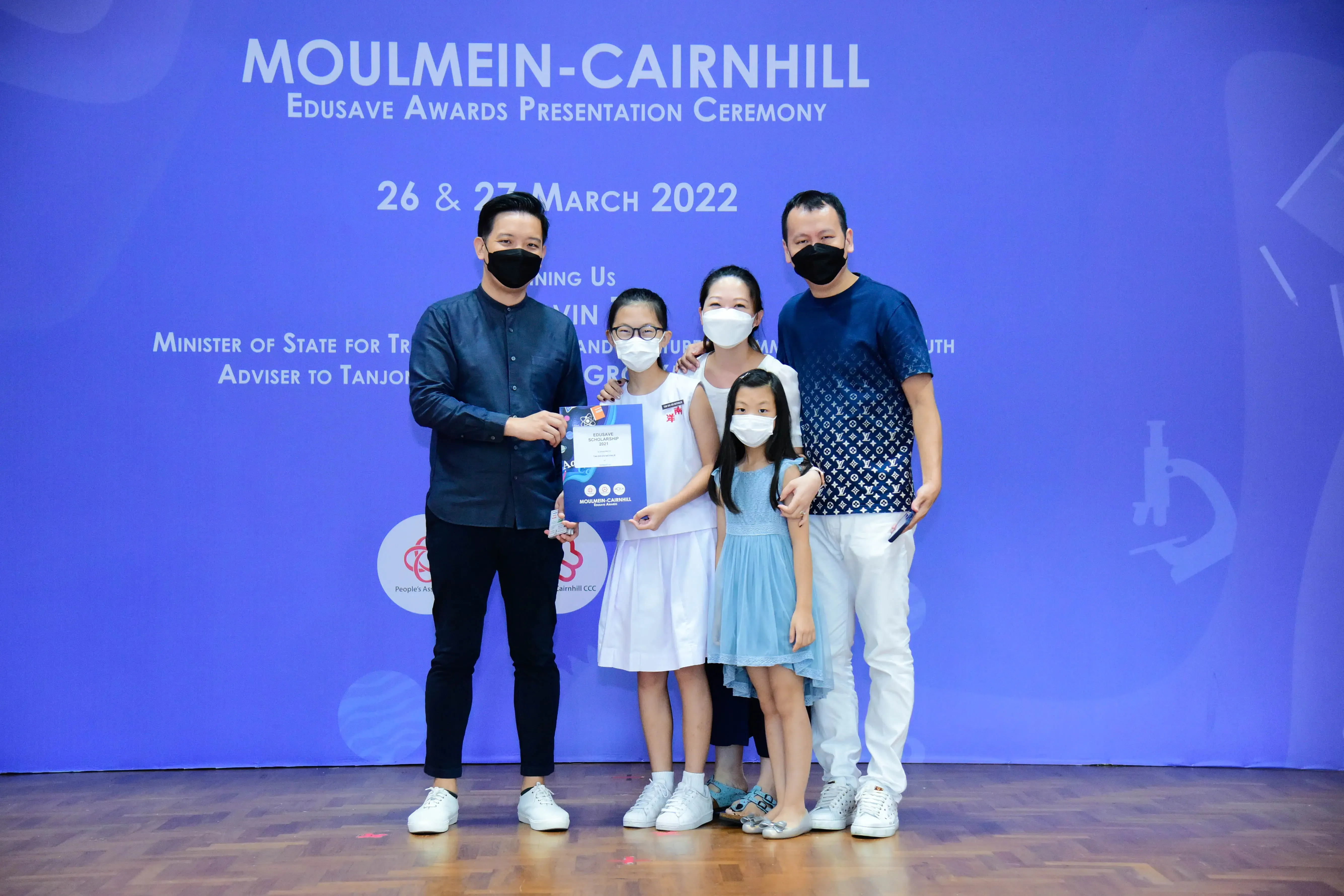 Five masked people pose with an award certificate at the Moulmein-Cairnhill Edusave Awards Presentation Ceremony, March 2022.