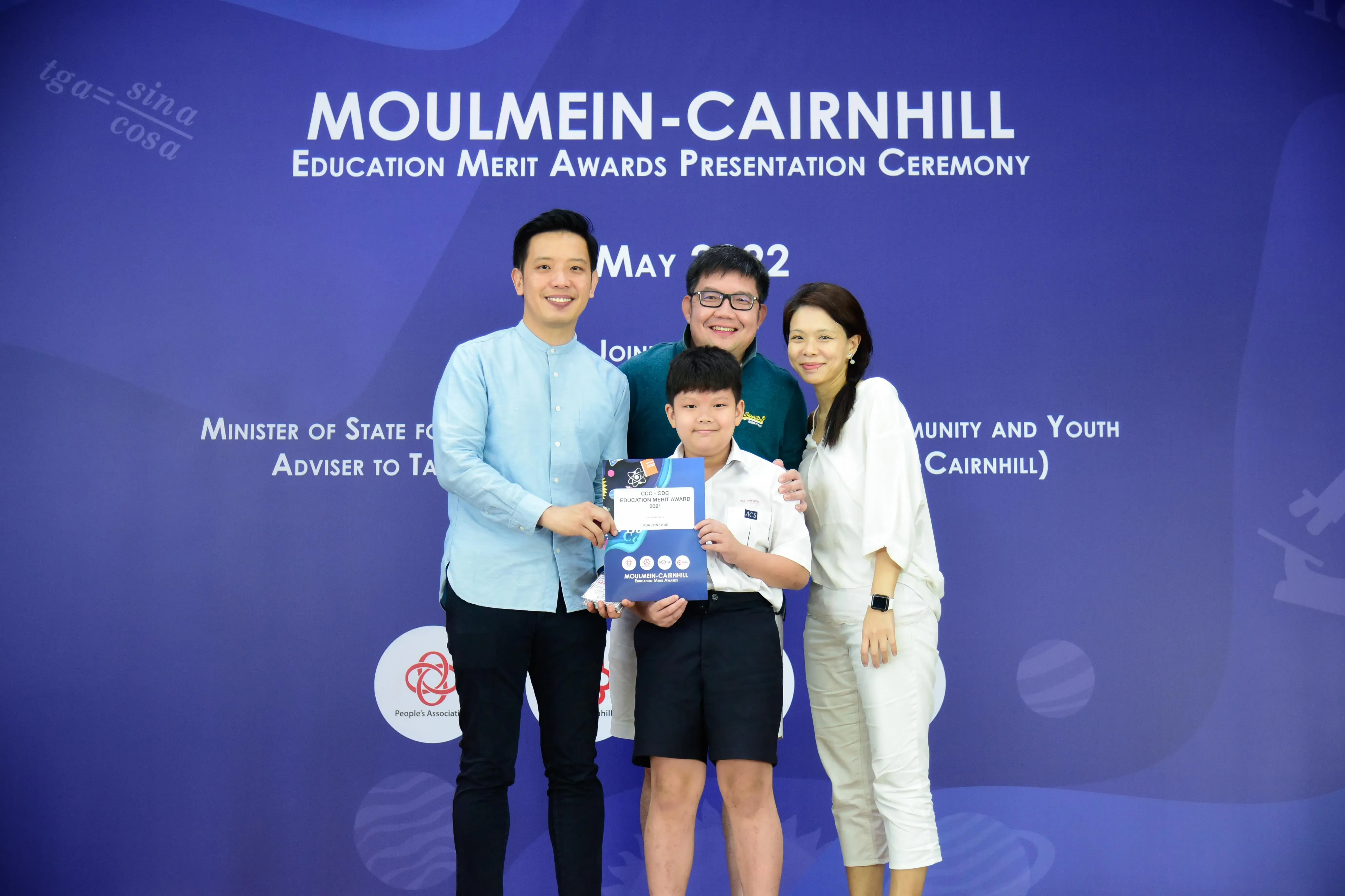 Three adults and a boy holding an award certificate pose at the Moulmein-Cairnhill Education Merit Awards ceremony.