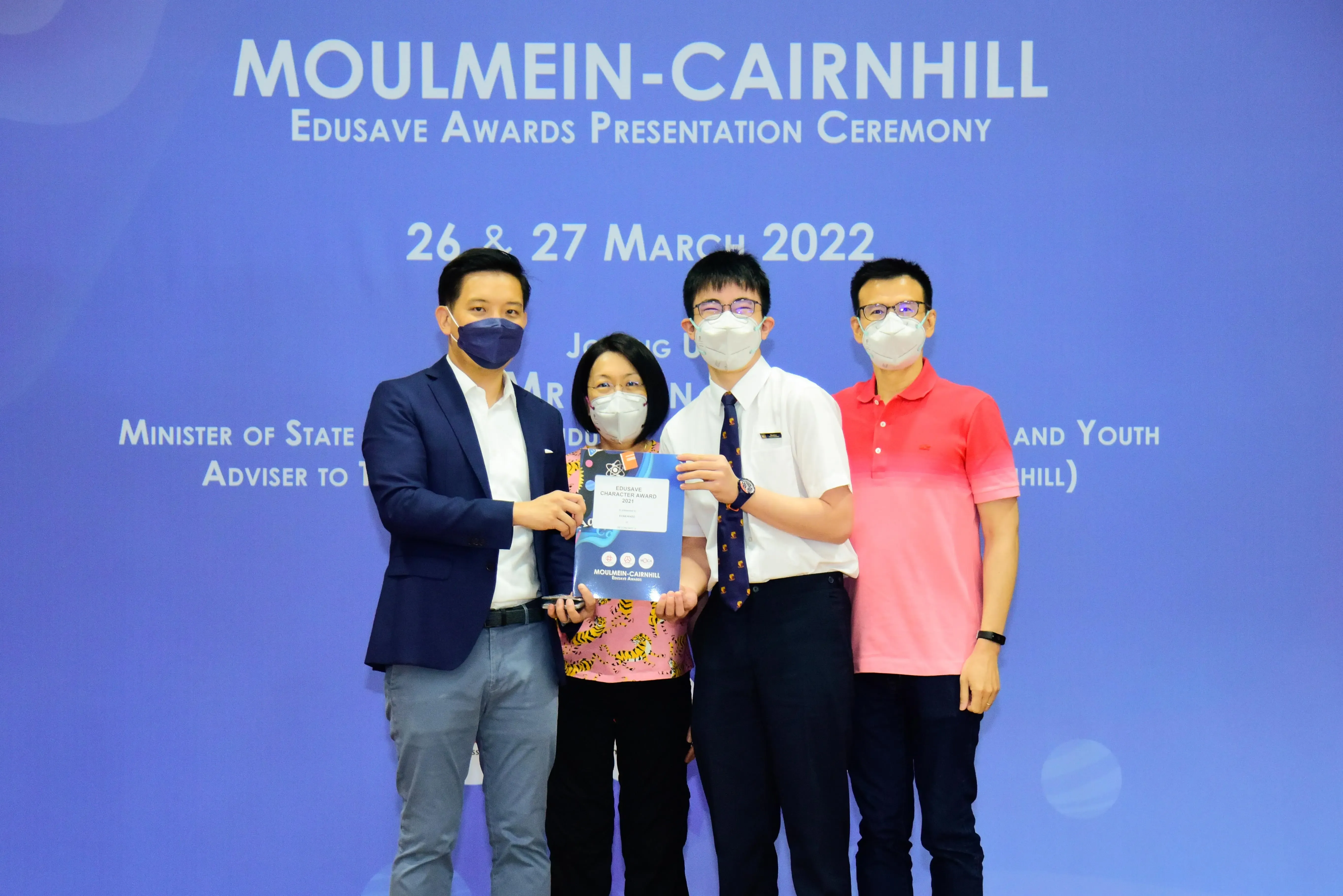 Four masked people pose at the Moulmein-Cairnhill Edusave Awards Presentation Ceremony on 26-27 March 2022.