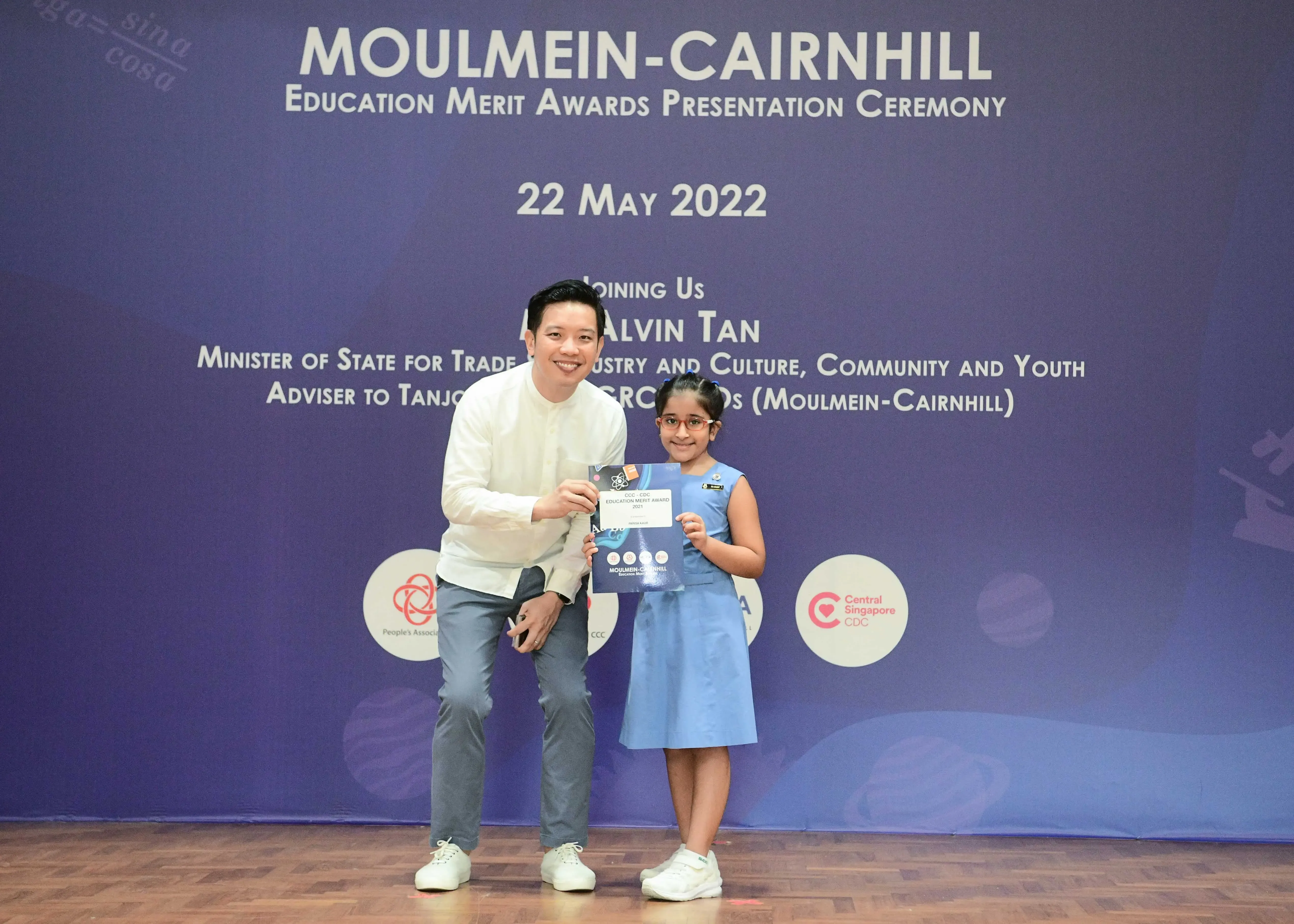 A man and a young girl hold an award certificate at the Moulmein-Cairnhill Education Merit Awards ceremony on 22 May 2022.