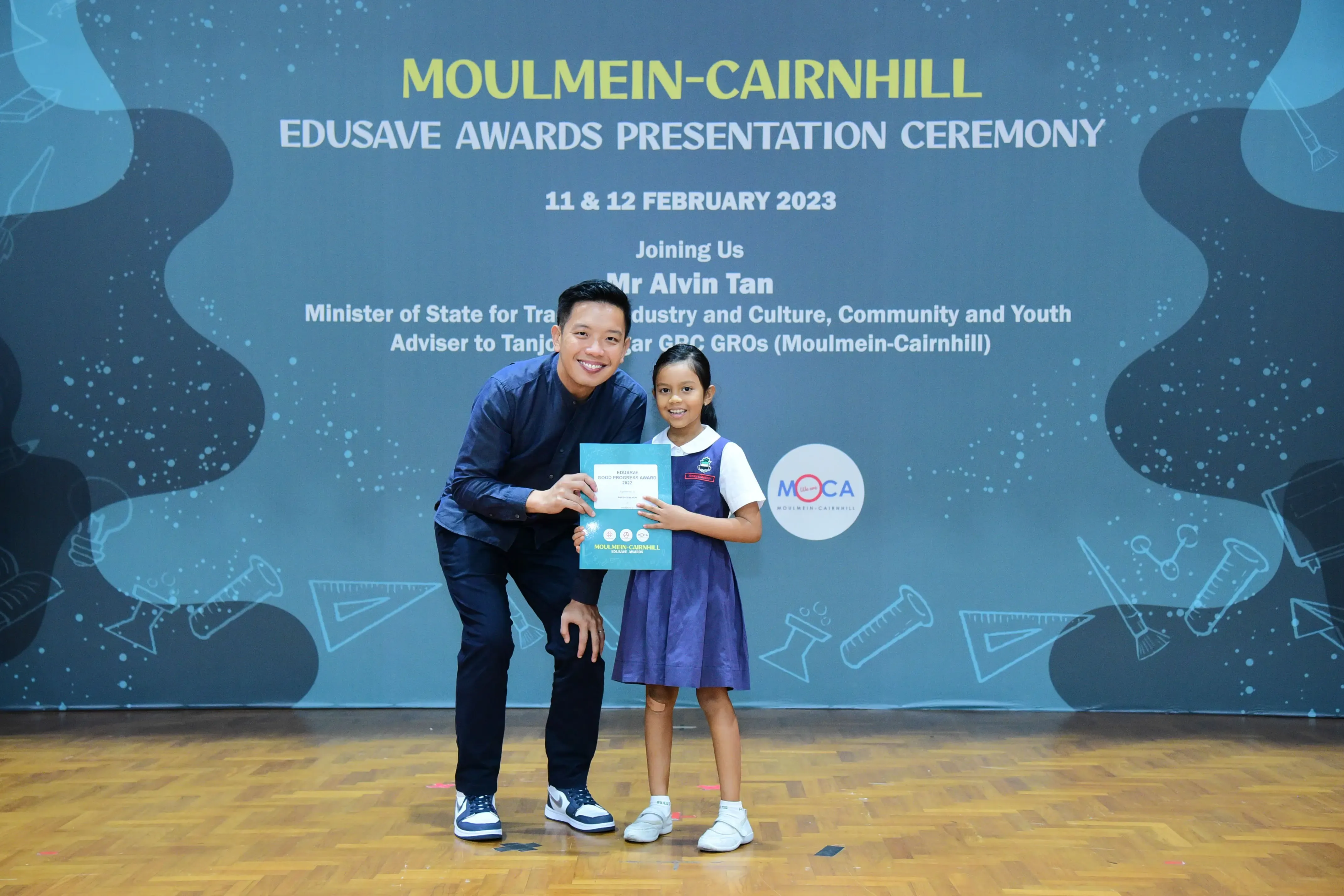 A man and a young girl hold a certificate at the Moulmein-Cairnhill Edusave Awards Ceremony, February 2023.