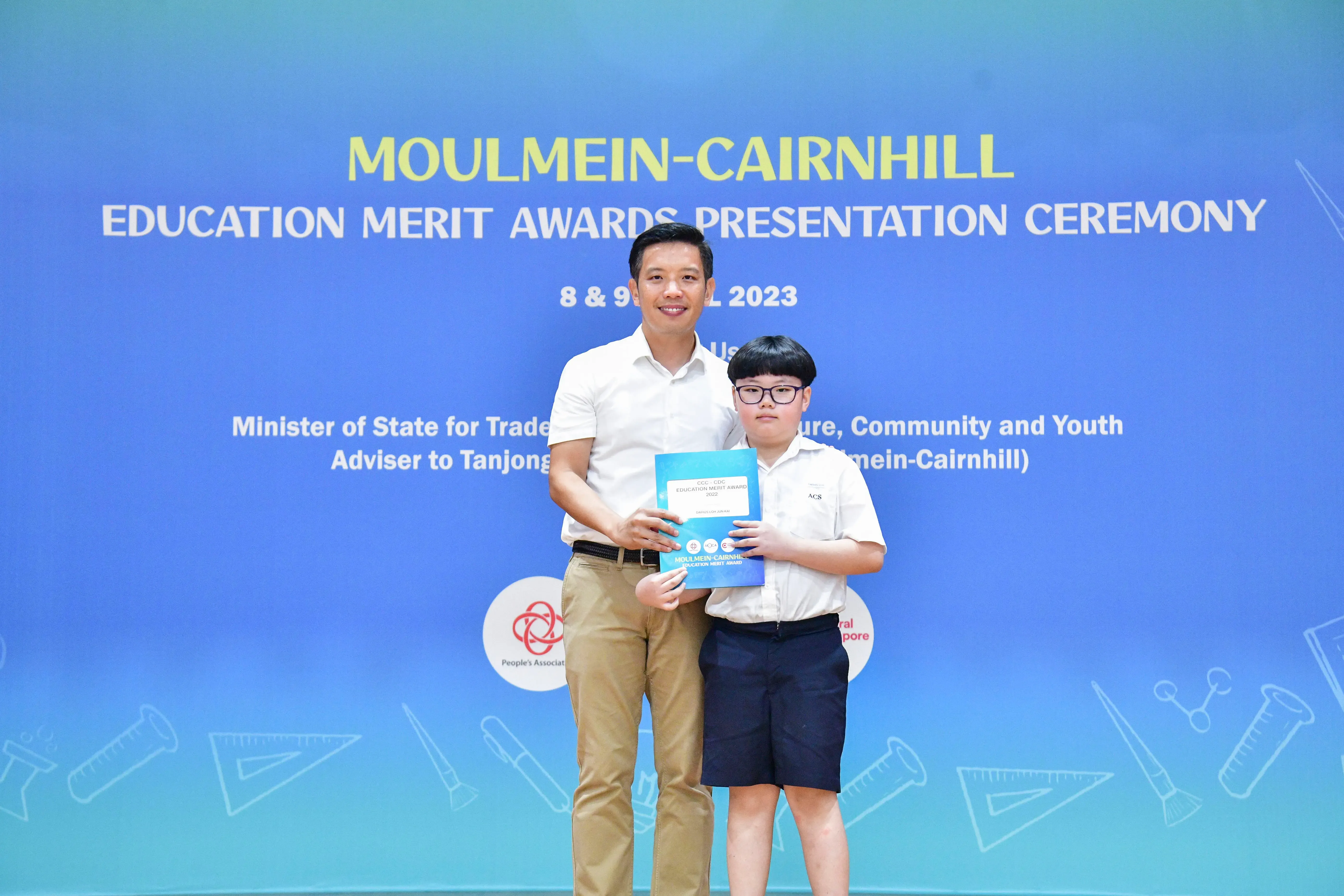 An adult and a young student pose together holding an award at the Moulmein-Cairnhill Education Merit Awards 2023.