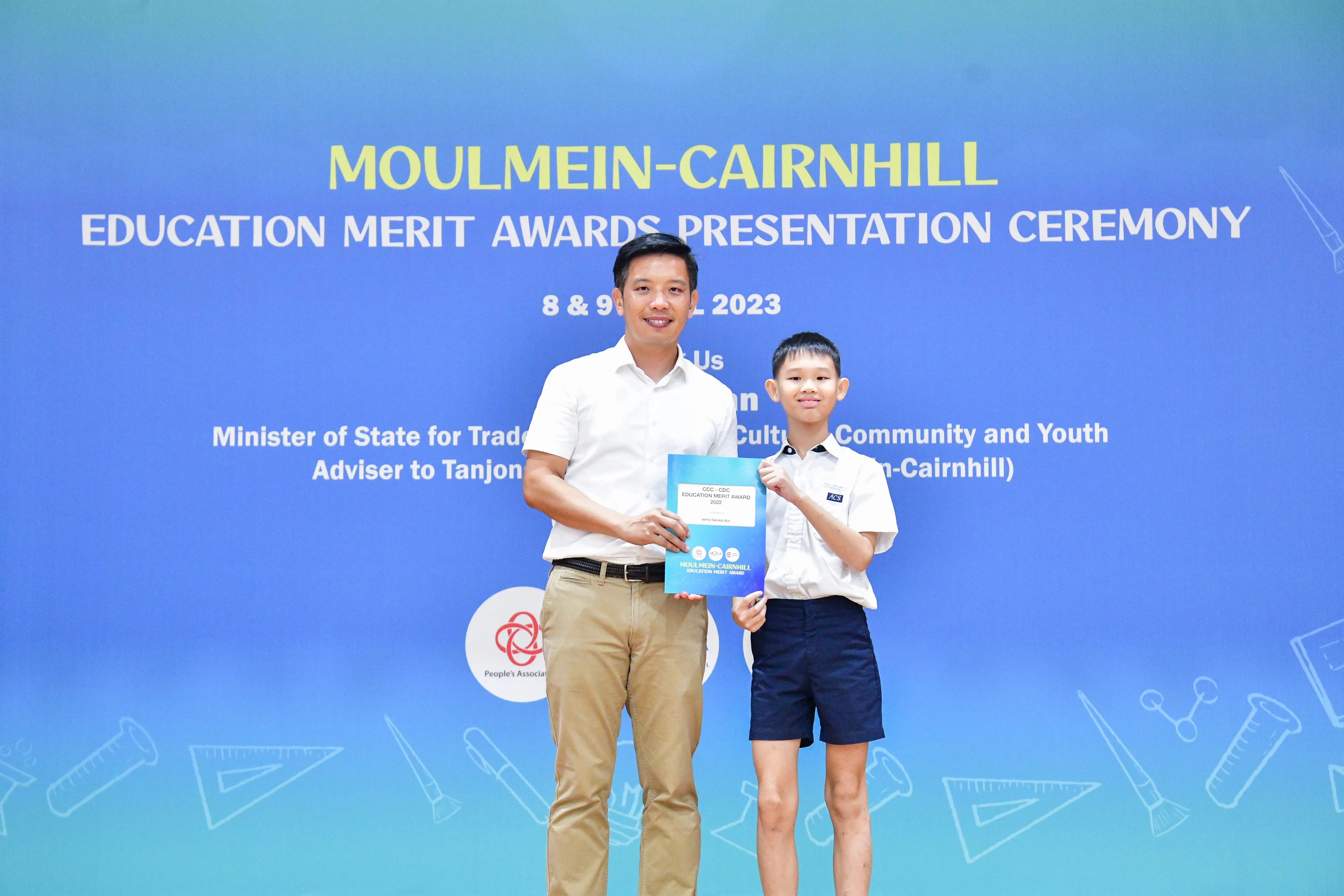 A man and a young boy hold a certificate at the Moulmein-Cairnhill Education Merit Awards Presentation Ceremony 2023.