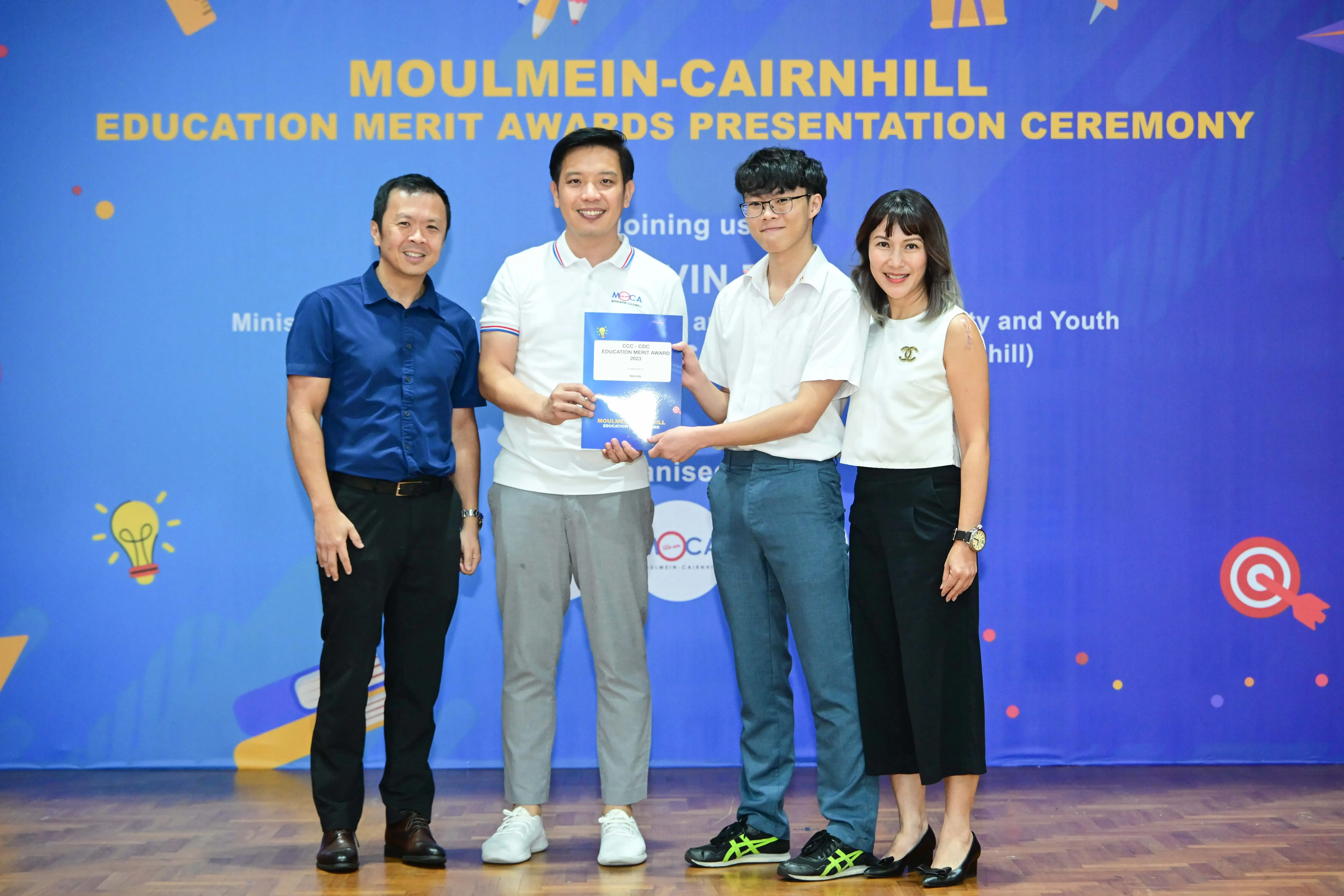 Four people pose at the Moulmein-Cairnhill Education Merit Awards Presentation Ceremony, two holding a certificate.