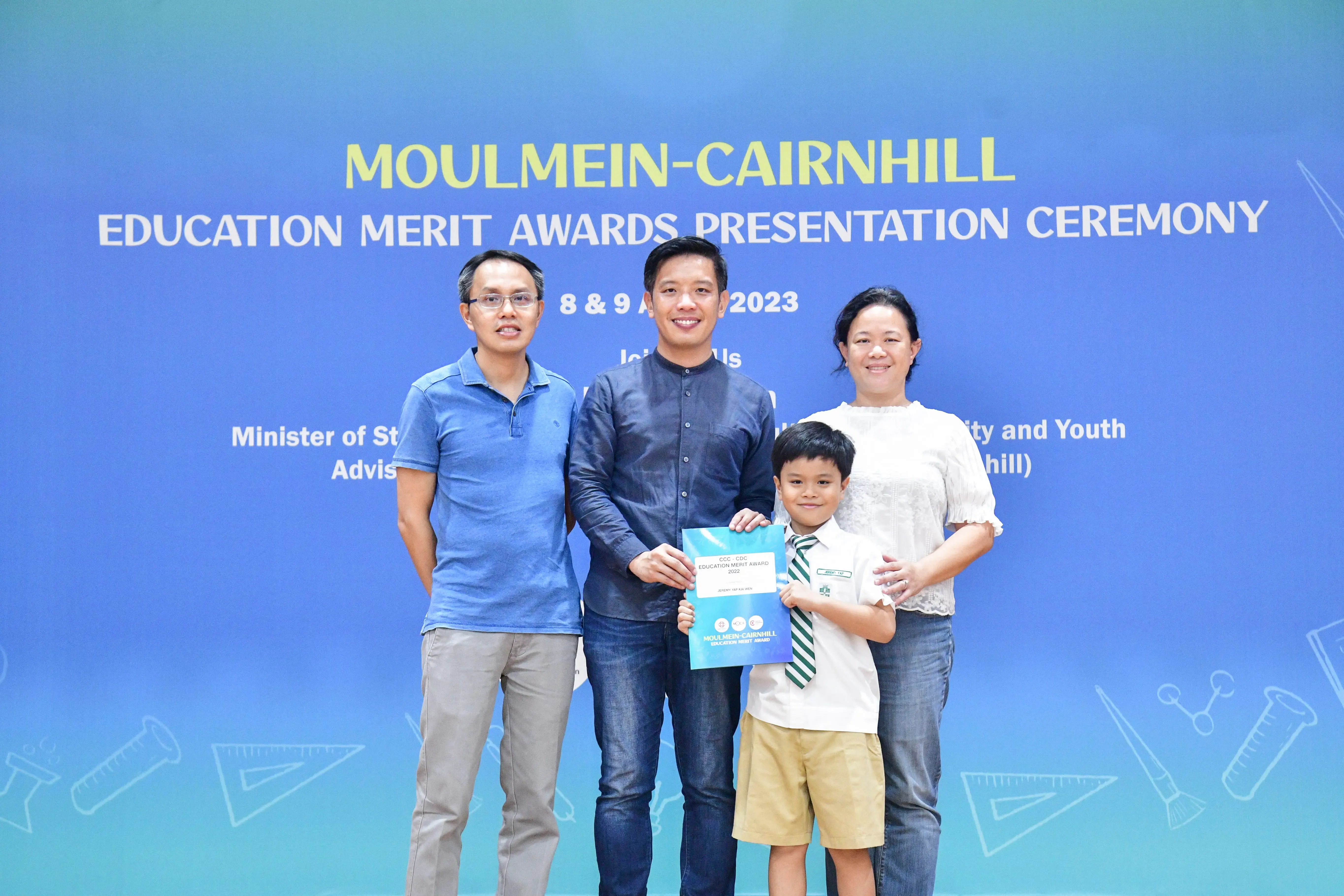 Three adults and a young boy holding an award certificate at the Moulmein-Cairnhill Education Merit Awards 2023.