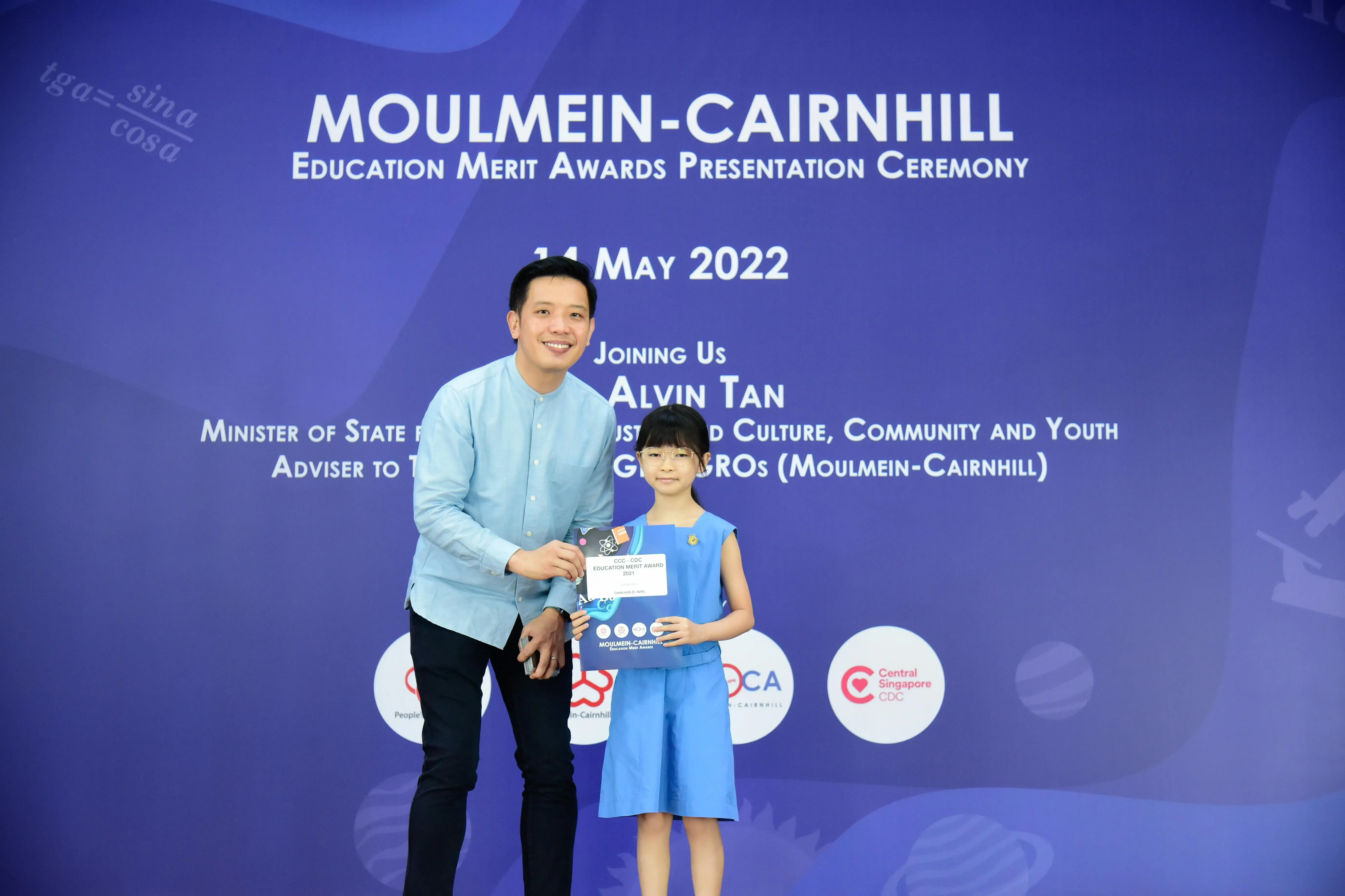 A man and a young girl hold an award certificate at the Moulmein-Cairnhill Education Merit Awards ceremony on 14 May 2022.