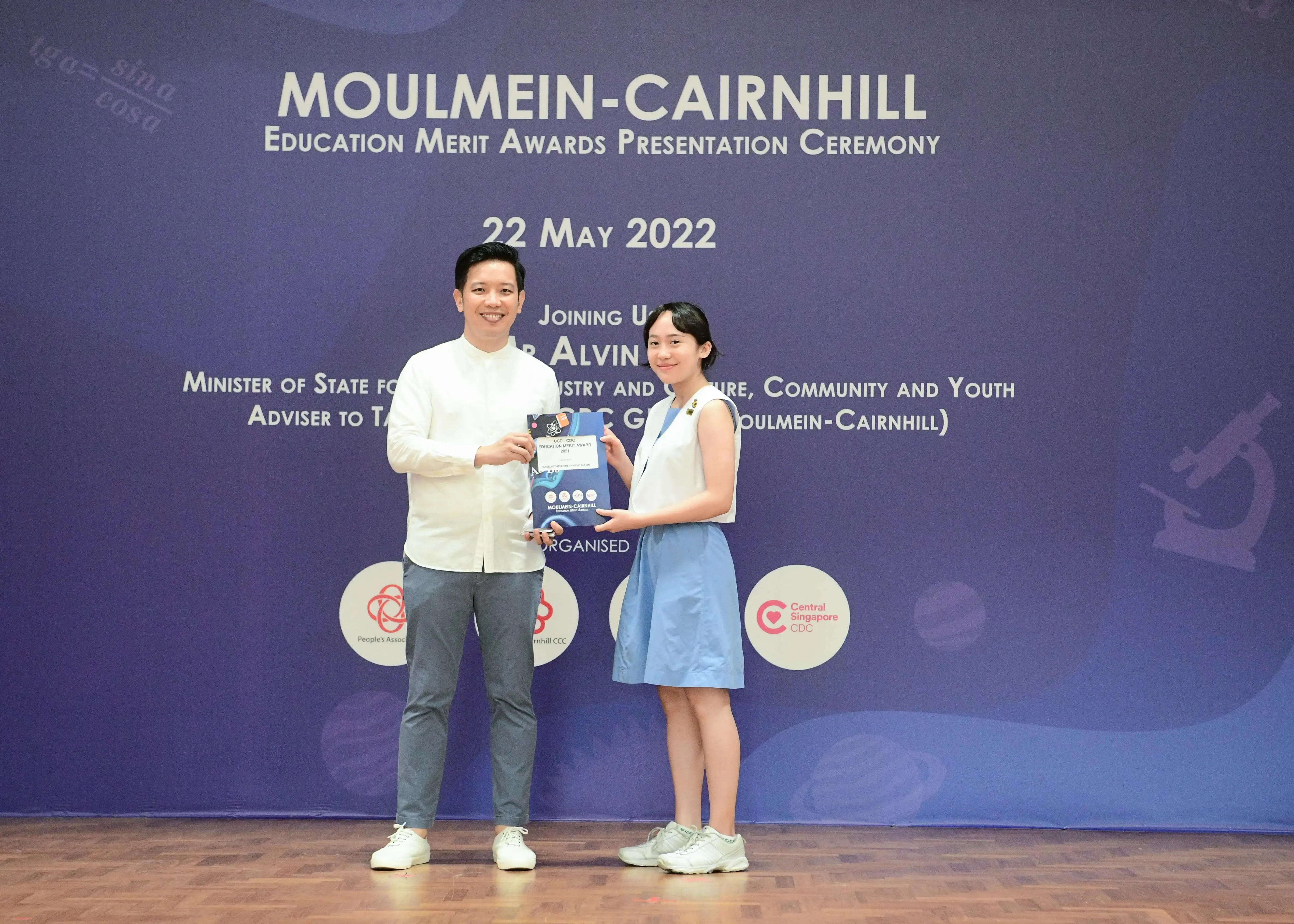 Two people hold an award booklet at the Moulmein-Cairnhill Education Merit Awards Ceremony on 22 May 2022.