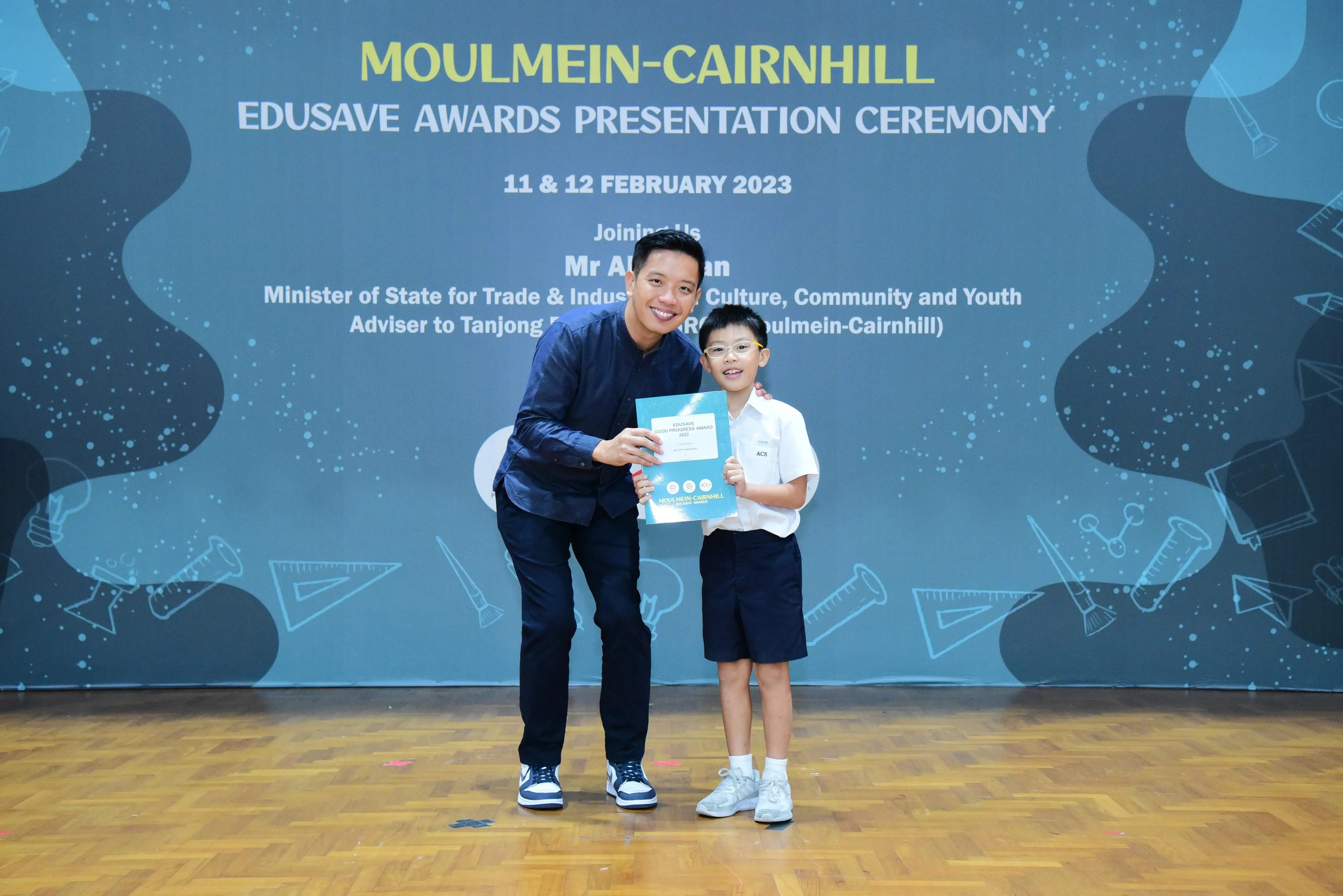 A man and a young boy holding a certificate at the Moulmein-Cairnhill Edusave Awards Presentation Ceremony 2023.