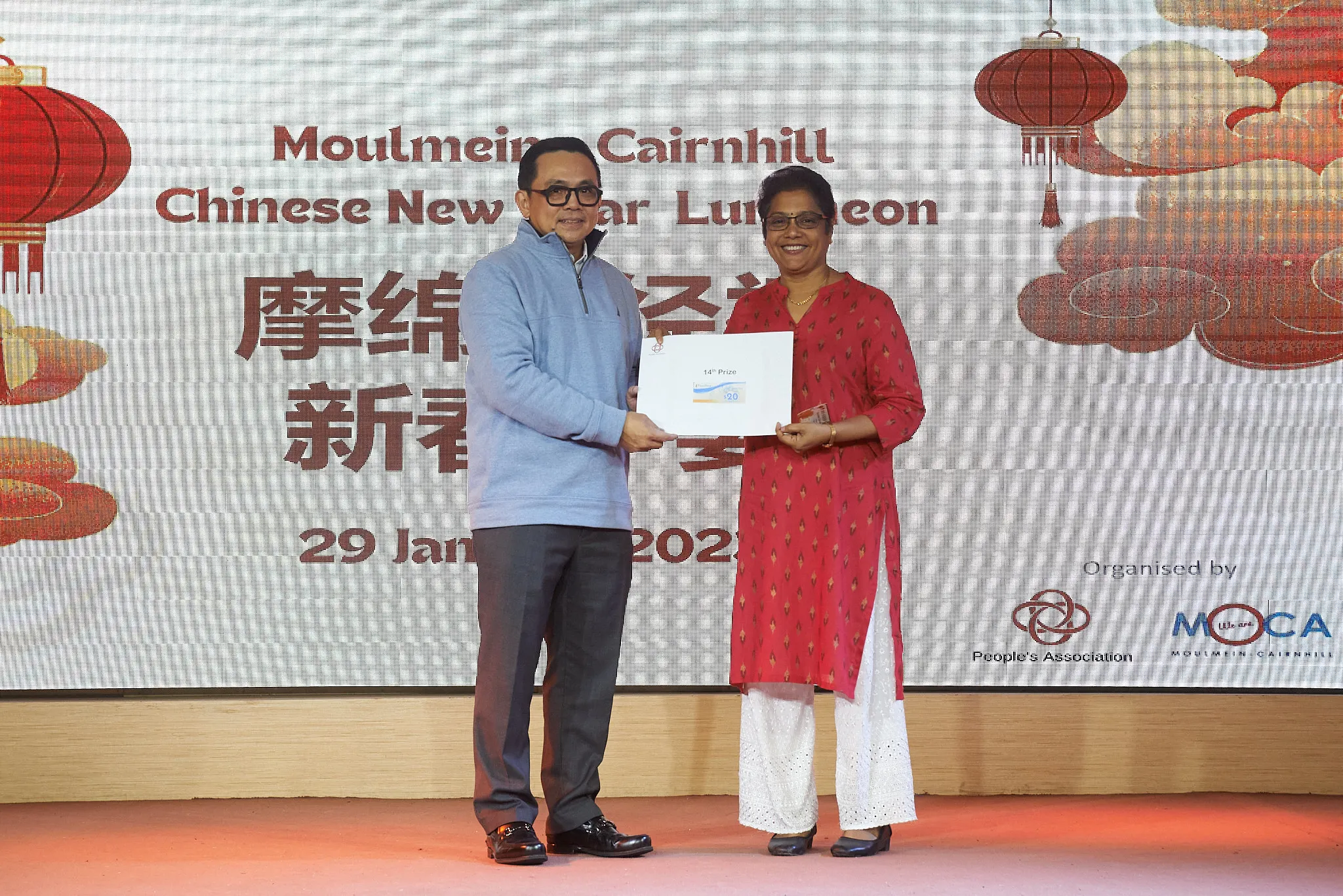 Two people holding a prize envelope at the Moulmein-Cairnhill Chinese New Year Luncheon on 29 January 2023.