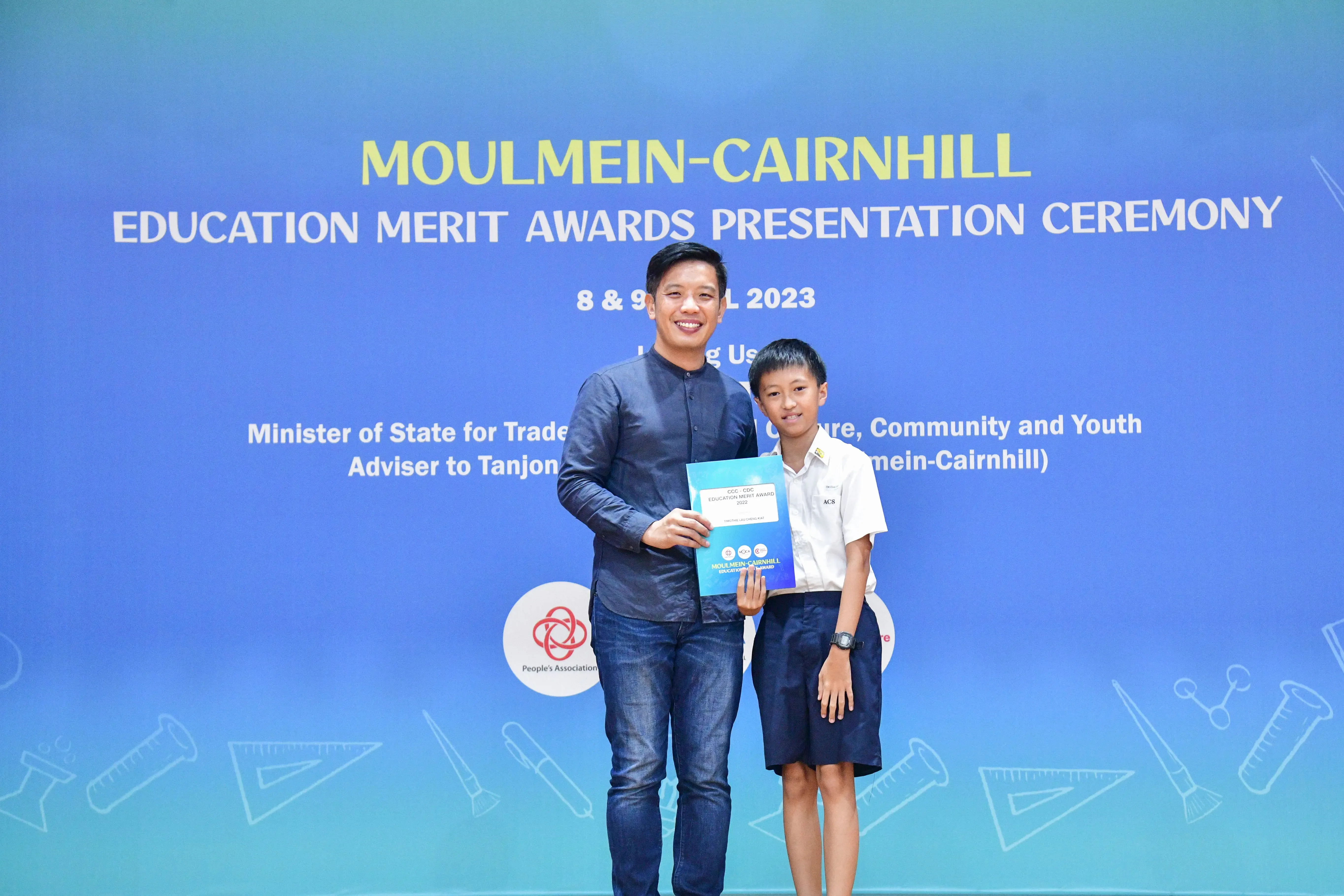 A man and a young boy hold a certificate together at the Moulmein-Cairnhill Education Merit Awards Ceremony 2023.