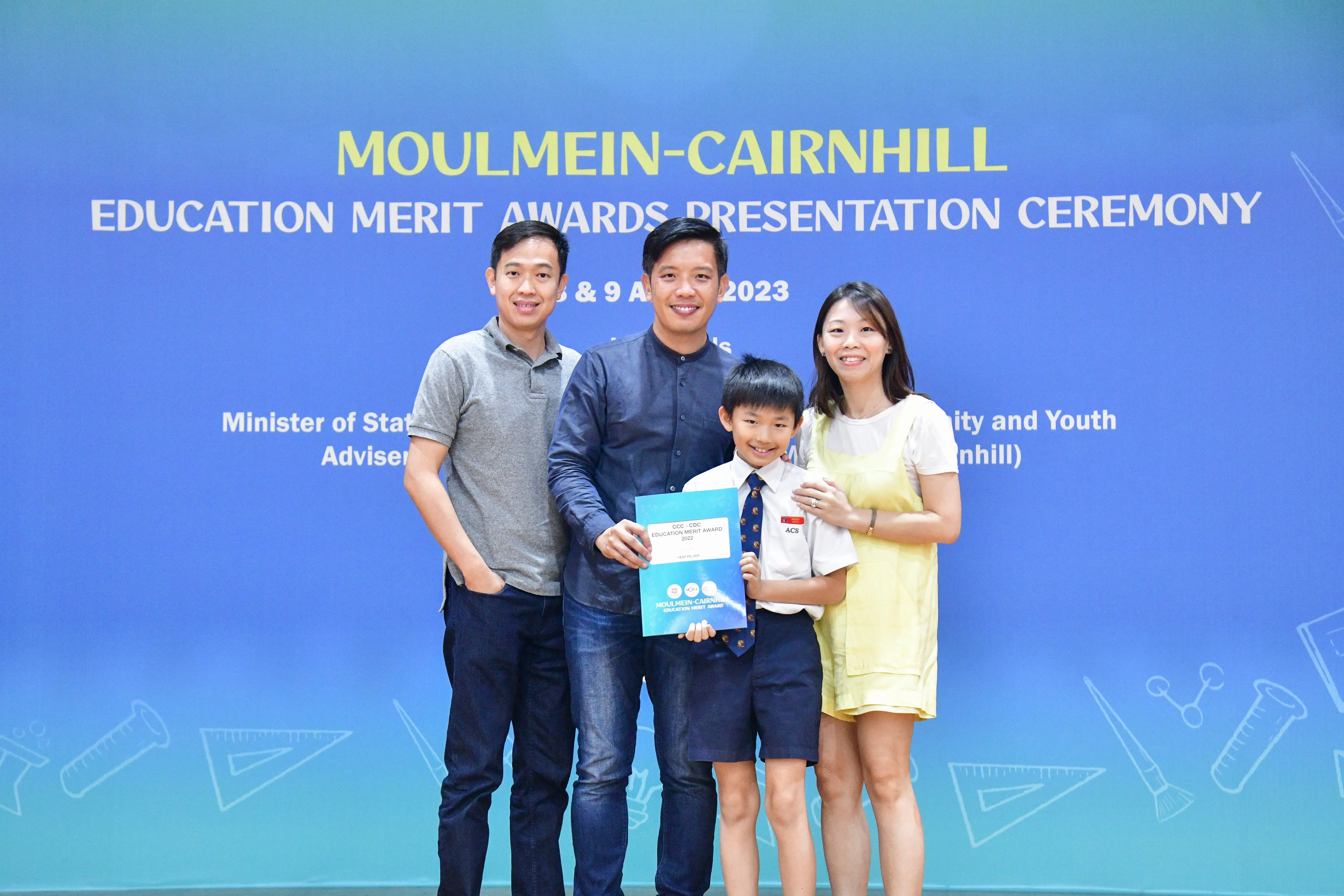 Three adults and a boy holding a certificate pose at the Moulmein-Cairnhill Education Merit Awards 2023.