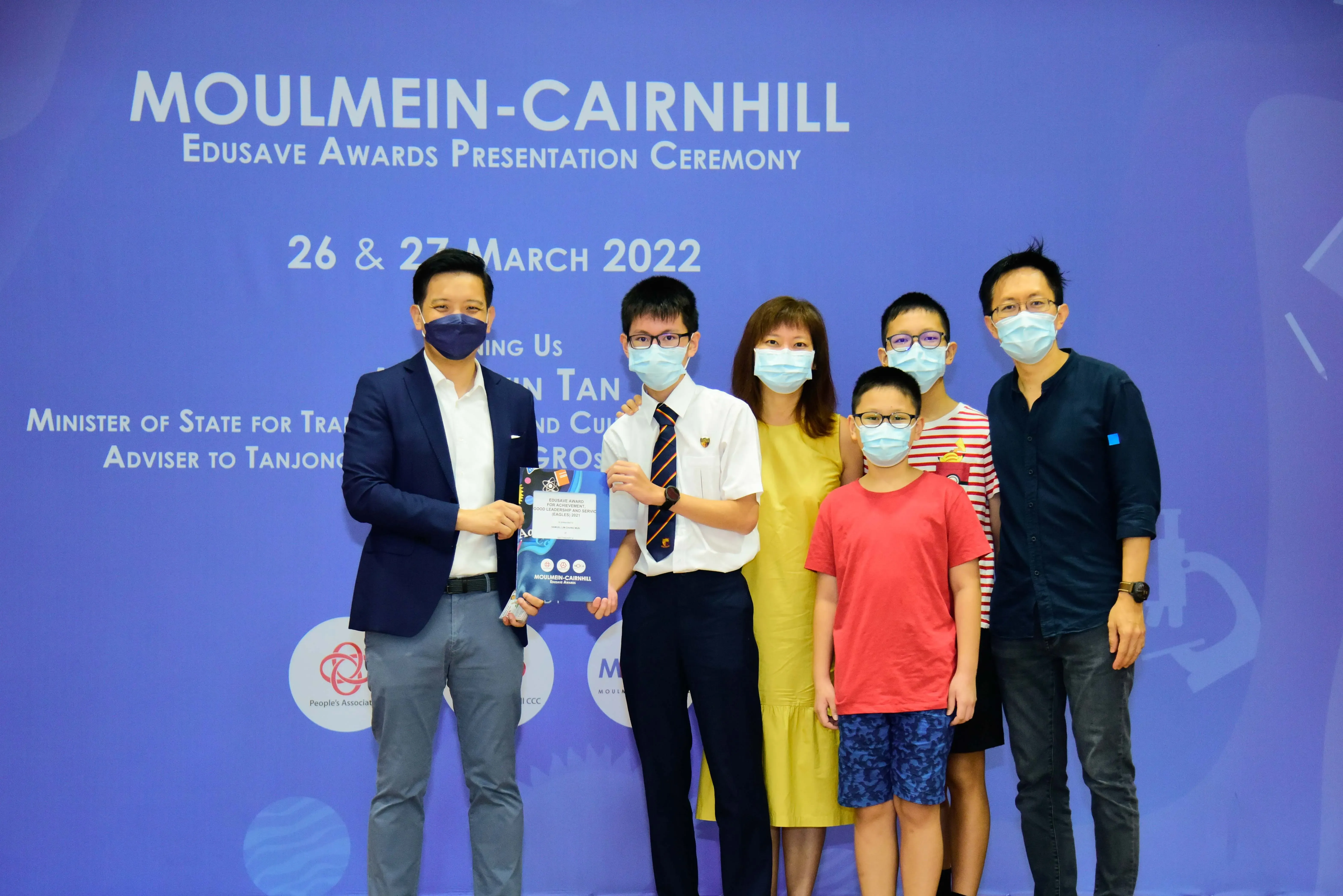 Six masked people pose at the Moulmein-Cairnhill Edusave Awards Presentation Ceremony on 26-27 March 2022.